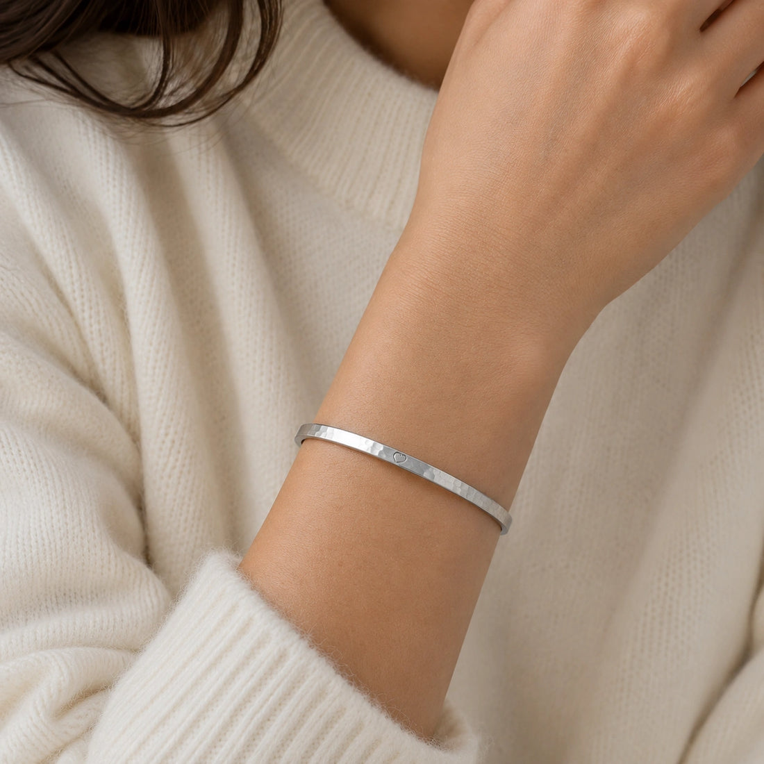 Gold_cuff_bracelet_in_gold_plated_silver_with_an_engraved_heart_at_front_angle_view_on_soft_fabric_background