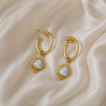 Gold_drop_earrings_in_gold_plated_silver_at_slightly_angled_with_triangle_moonstone_charms_on_soft_fabric_background