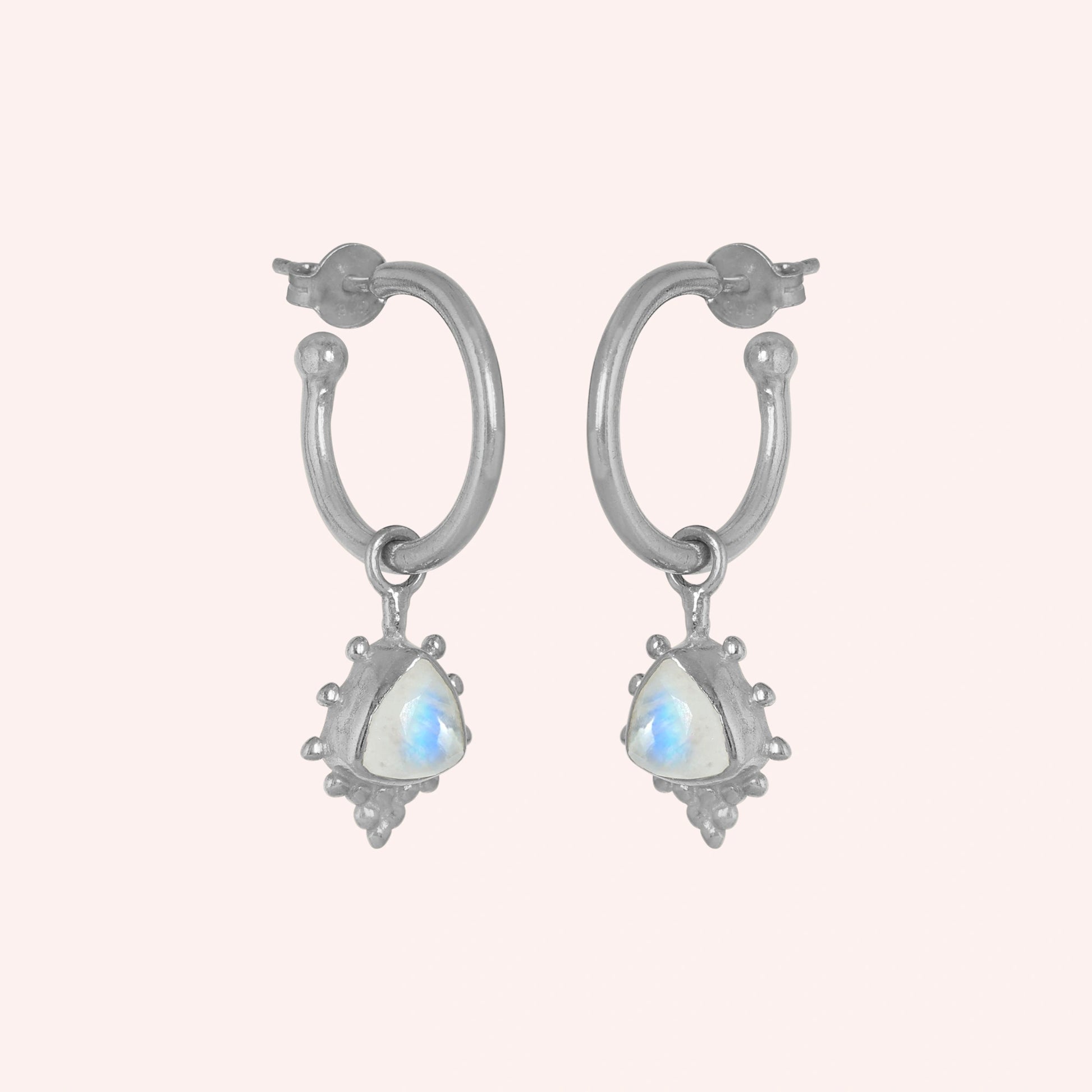 Gold_drop_earrings_in_sterling_silver_at_slightly_angled_with_triangle_moonstone_charms_on_solid_pink_background