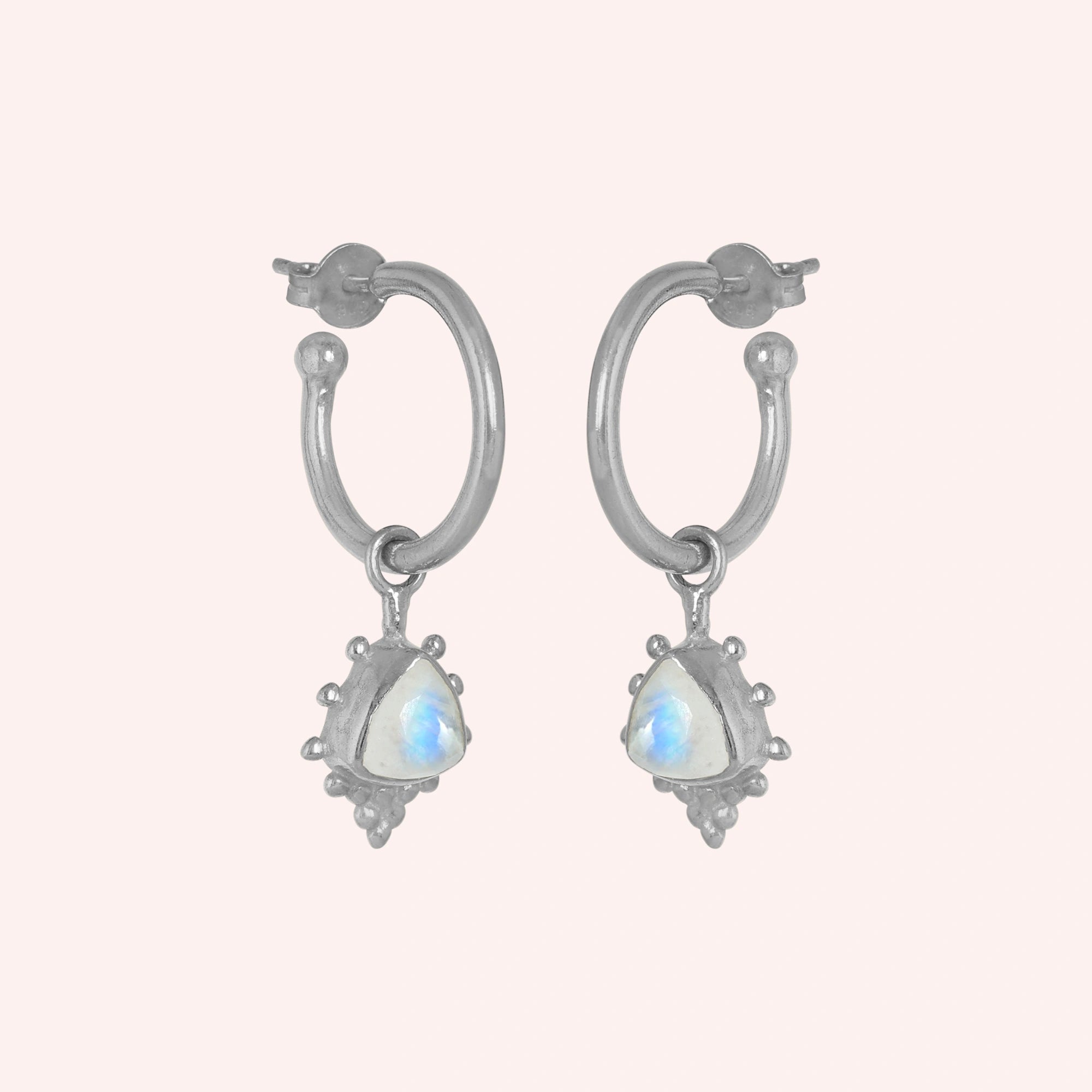 Gold_drop_earrings_in_sterling_silver_at_slightly_angled_with_triangle_moonstone_charms_on_solid_pink_background