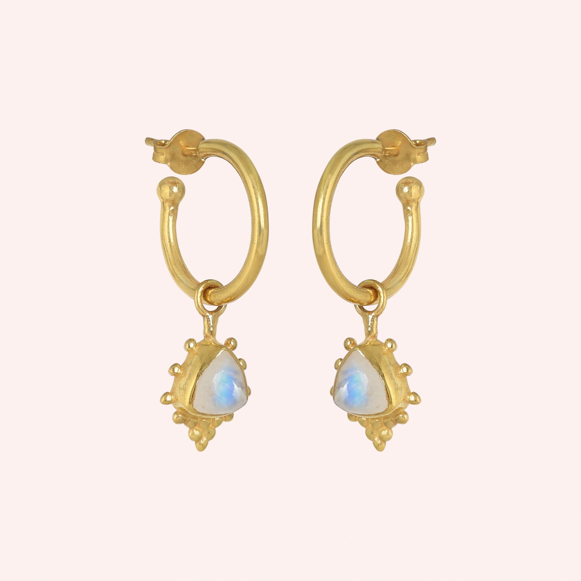 Gold_drop_earrings_in_gold_plated_silver_at_slightly_angled_with_triangle_moonstone_charms_on_solid_pink_background