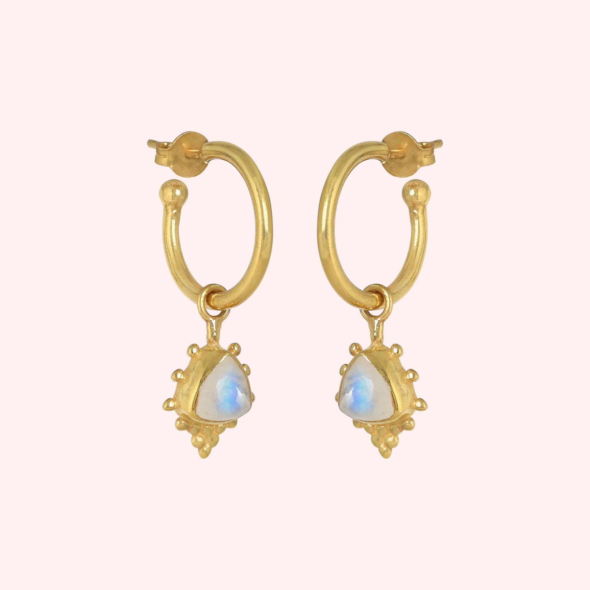 Gold_drop_earrings_in_gold_plated_silver_at_slightly_angled_with_triangle_moonstone_charms_on_solid_pink_background