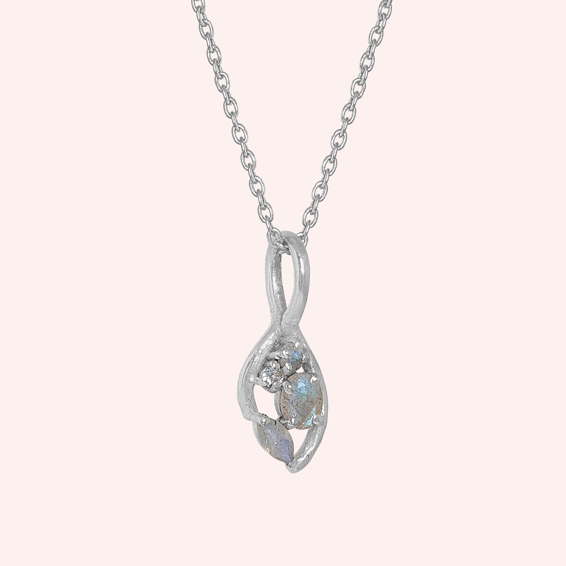 Gold_pendant_necklace_sterling_silver_on_slightly_angled_with_labradorite_gemstones_and_floral_details_on_solid_pink_background