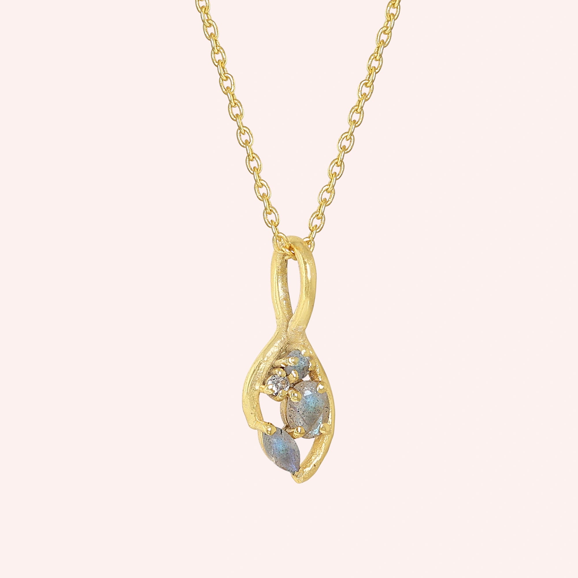 Gold_pendant_necklace_gold_plated_silver_on_slightly_angled_with_labradorite_gemstones_and_floral_details_on_solid_pink_background
