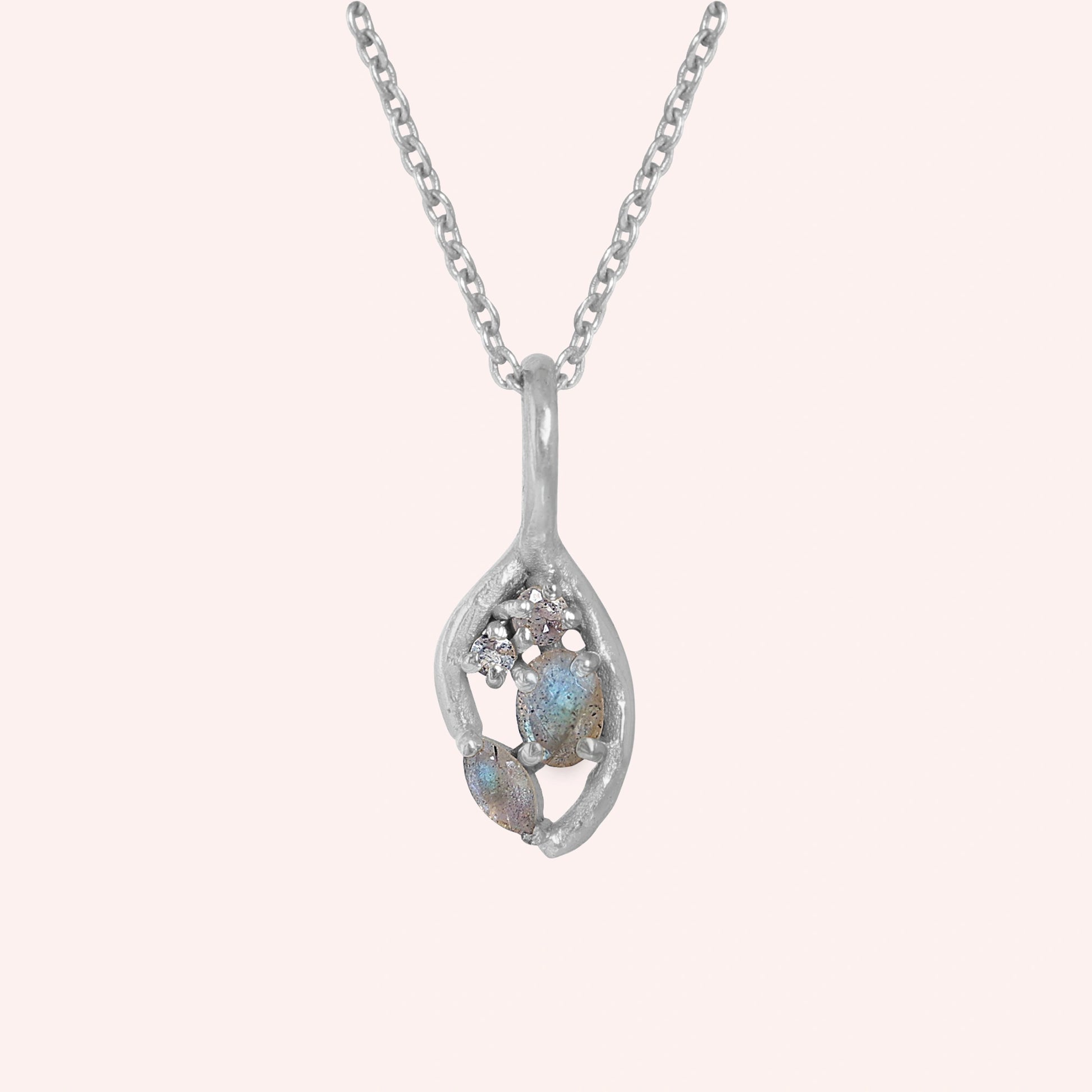 Gold_pendant_necklace_sterling_silver_on_front_angle_with_labradorite_gemstones_and_floral_details_on_solid_pink_background