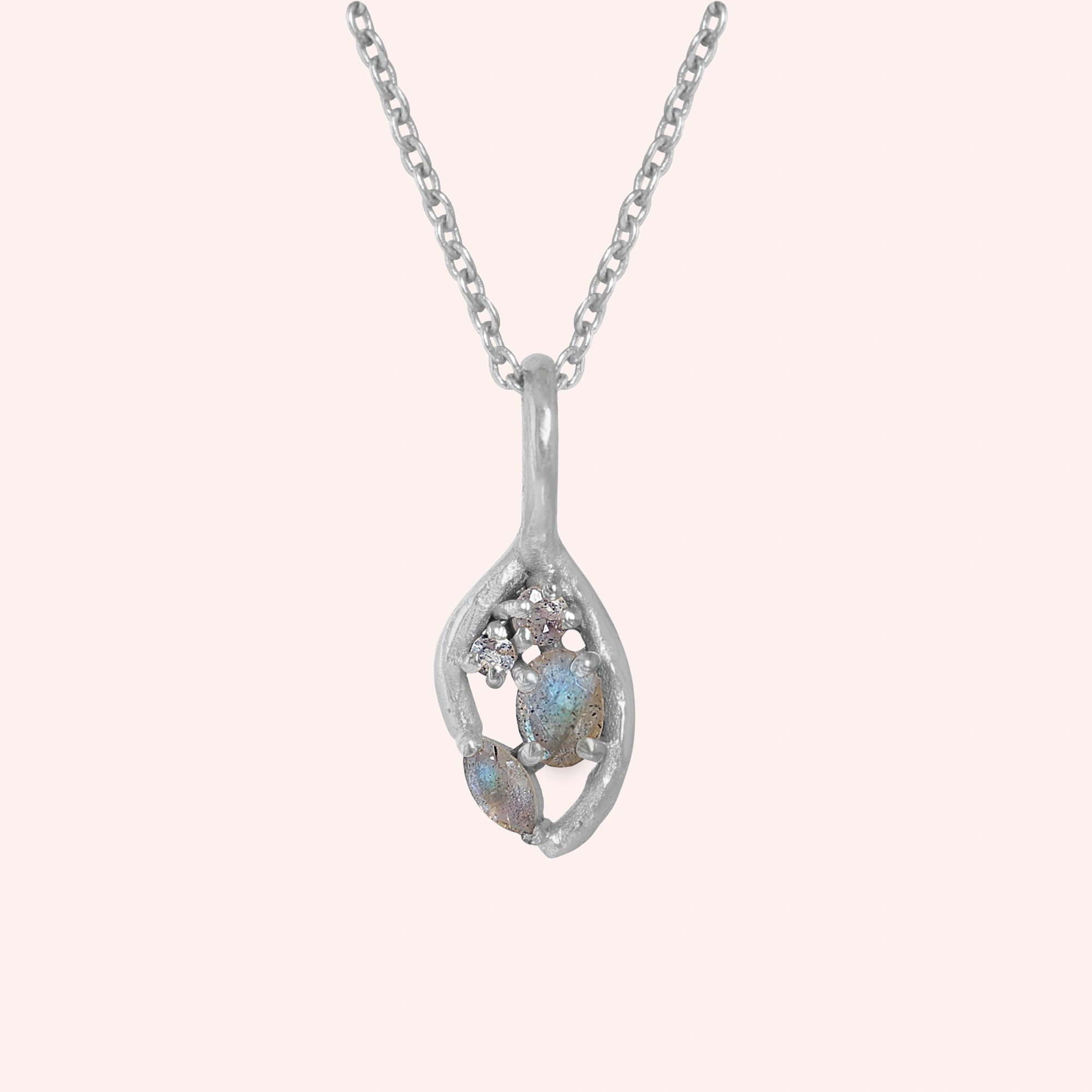 Gold_pendant_necklace_sterling_silver_on_front_angle_with_labradorite_gemstones_and_floral_details_on_solid_pink_background