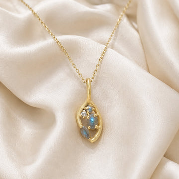 Gold_pendant_necklace_gold_plated_on_front_angle_with_labradorite_gemstones_and_floral_details_on_soft_fabric_background