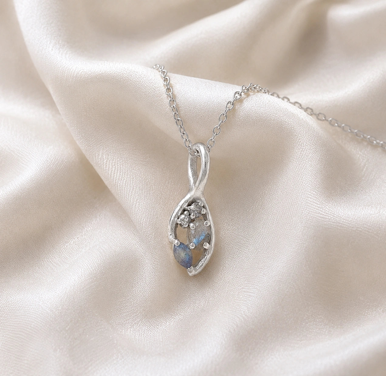 Gold_pendant_necklace_sterling_silver_on_slightly_angled_with_labradorite_gemstones_and_floral_details_on_soft_fabric_background