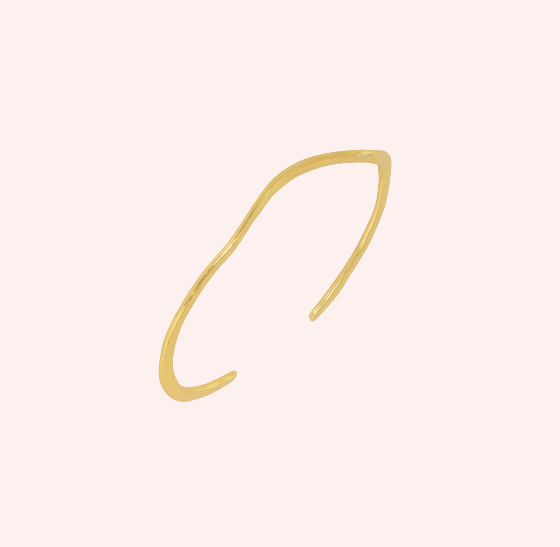 Gold_plated_bracelet_in_gold_plated_silver_with_textured_wavy_band_at_slight_angle_view_on_solid_pink_background