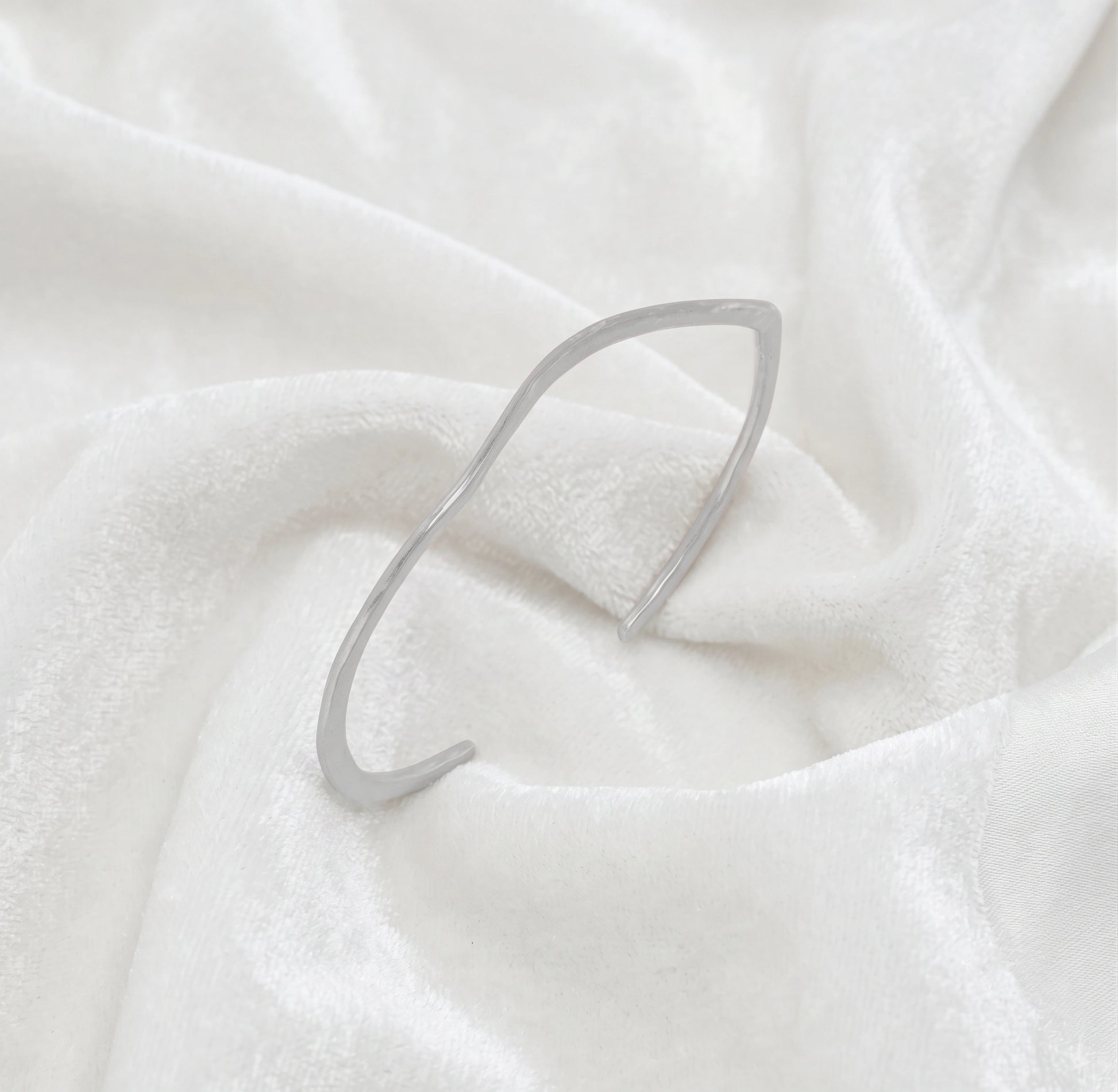 Gold_plated_bracelet_in_sterling_silver_with_textured_wavy_band_at_slight_angle_view_on_soft_fabric_background