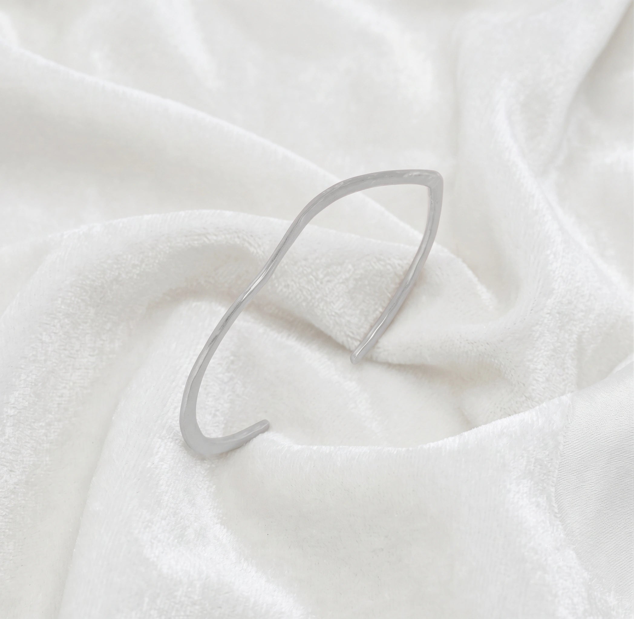 Gold_plated_bracelet_in_sterling_silver_with_textured_wavy_band_at_slight_angle_view_on_soft_fabric_background