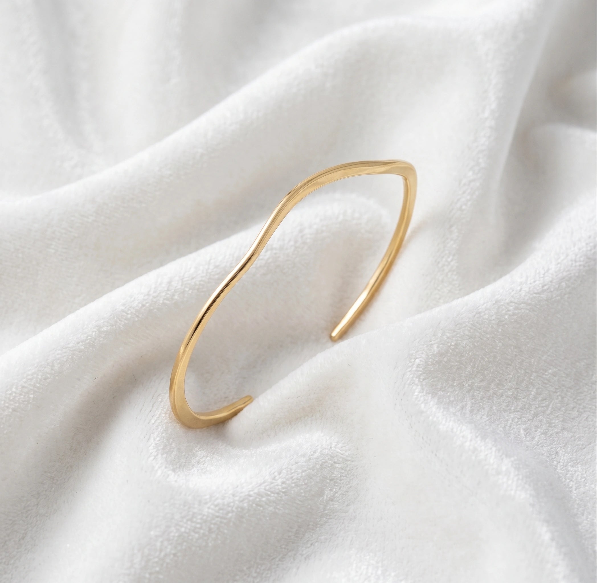 Gold_plated_bracelet_in_gold_plated_silver_with_textured_wavy_band_at_slight_angle_view_on_soft_fabric_background