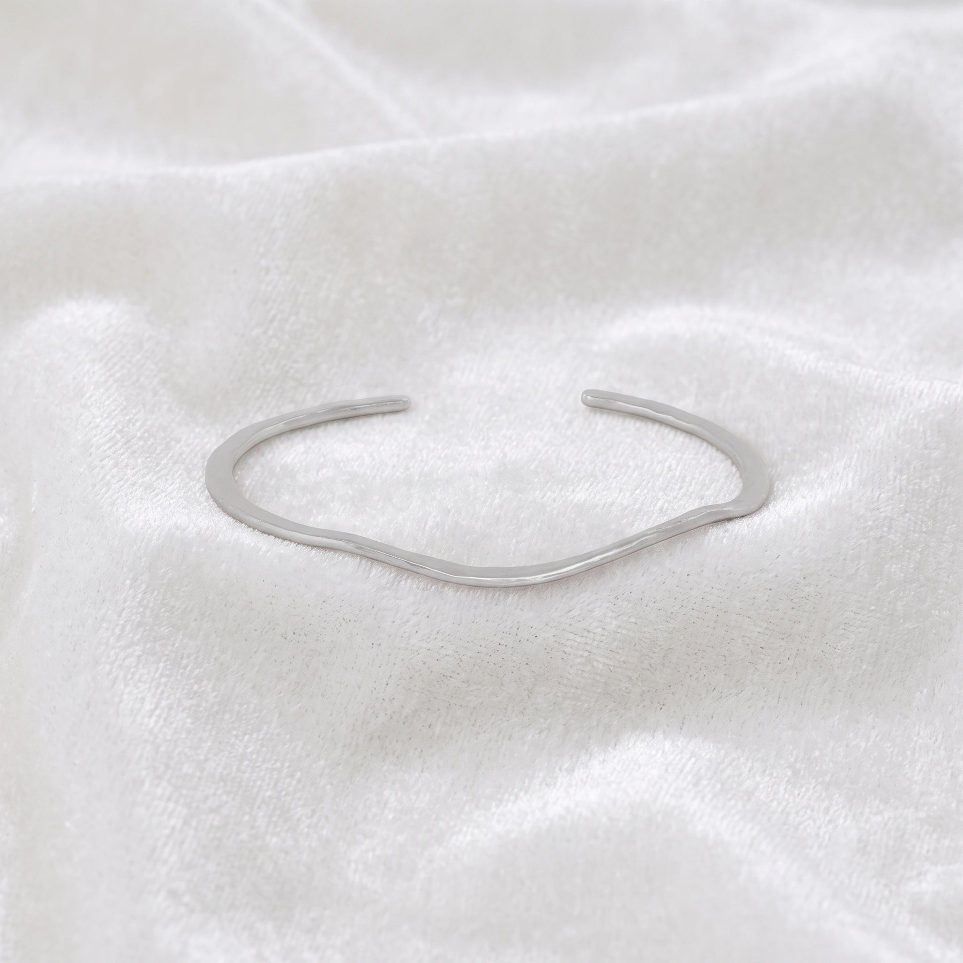 Gold_plated_bracelet_in_sterling_silver_with_textured_wavy_band_at_front_angle_view_on_soft_fabric_background