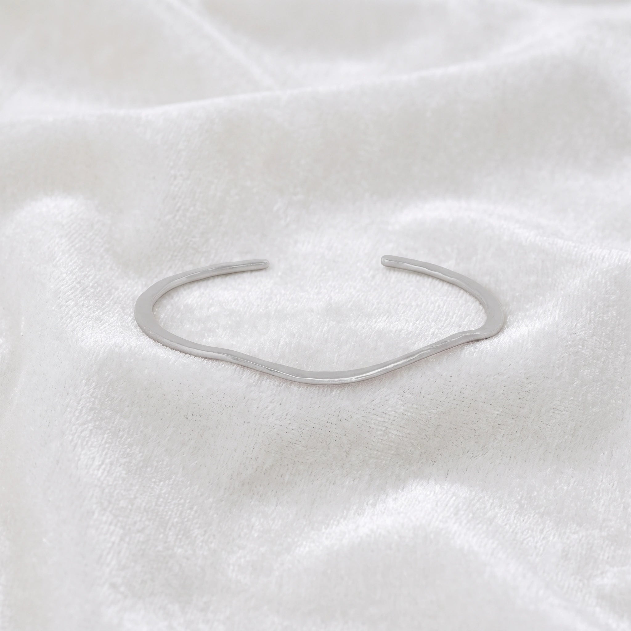 Gold_plated_bracelet_in_sterling_silver_with_textured_wavy_band_at_front_angle_view_on_soft_fabric_background