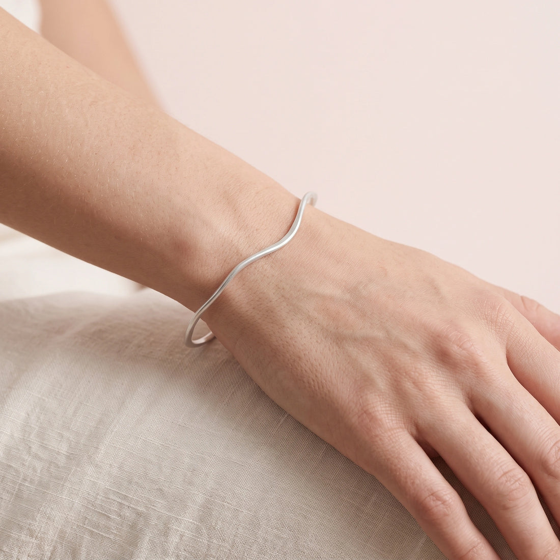 Gold_plated_bracelet_in_gold_plated_silver_with_textured_wavy_band_at_slight_angle_view_on_soft_fabric_background