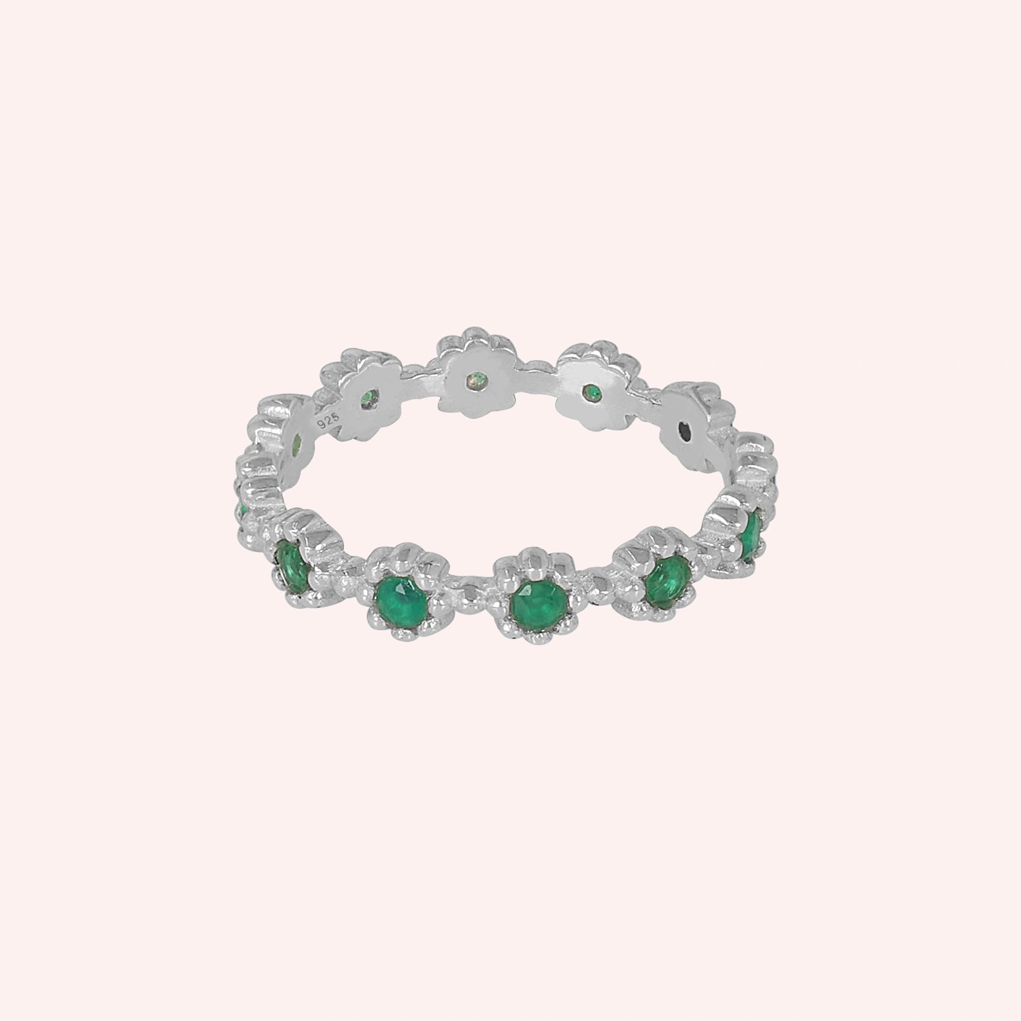 Sterling silver onyx ring flower band featuring green round stones ring is centered on a light pink background.