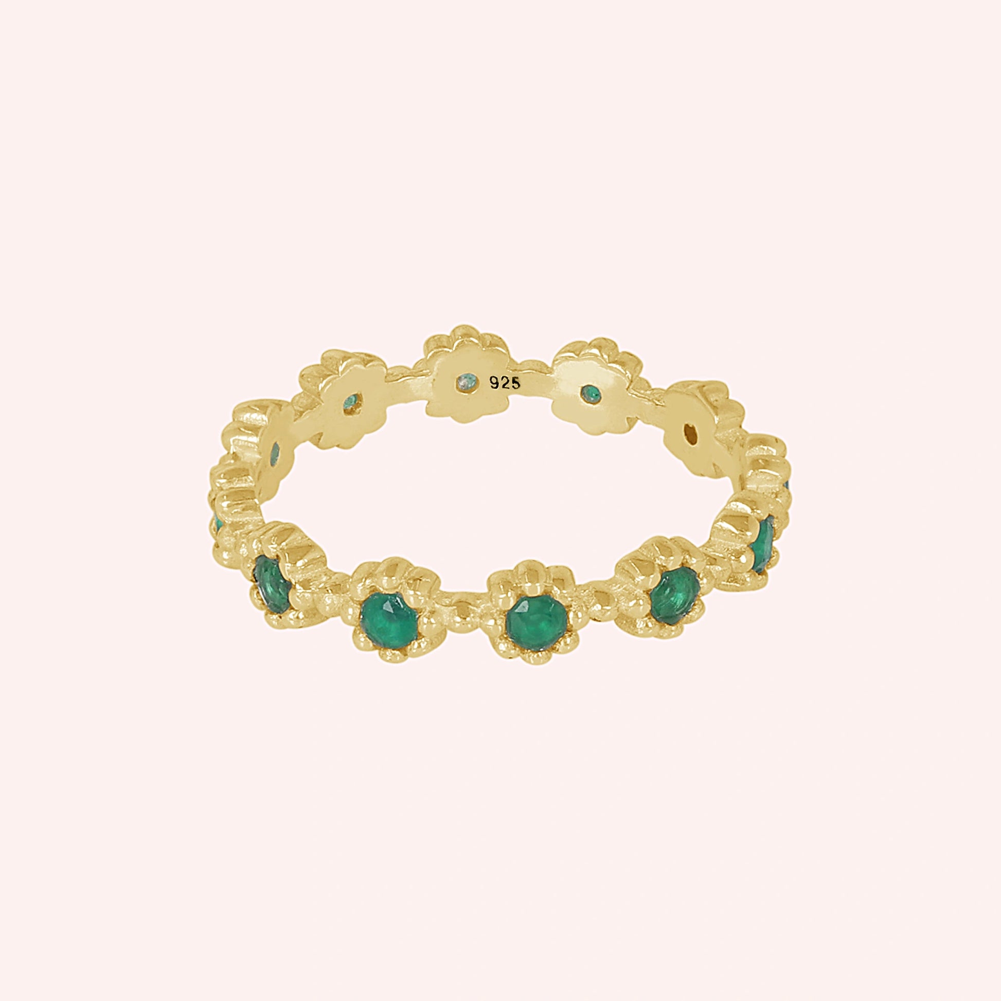 Full-view studio shot of a gold-plated sterling silver onyx ring with a floral pattern on a soft pink background