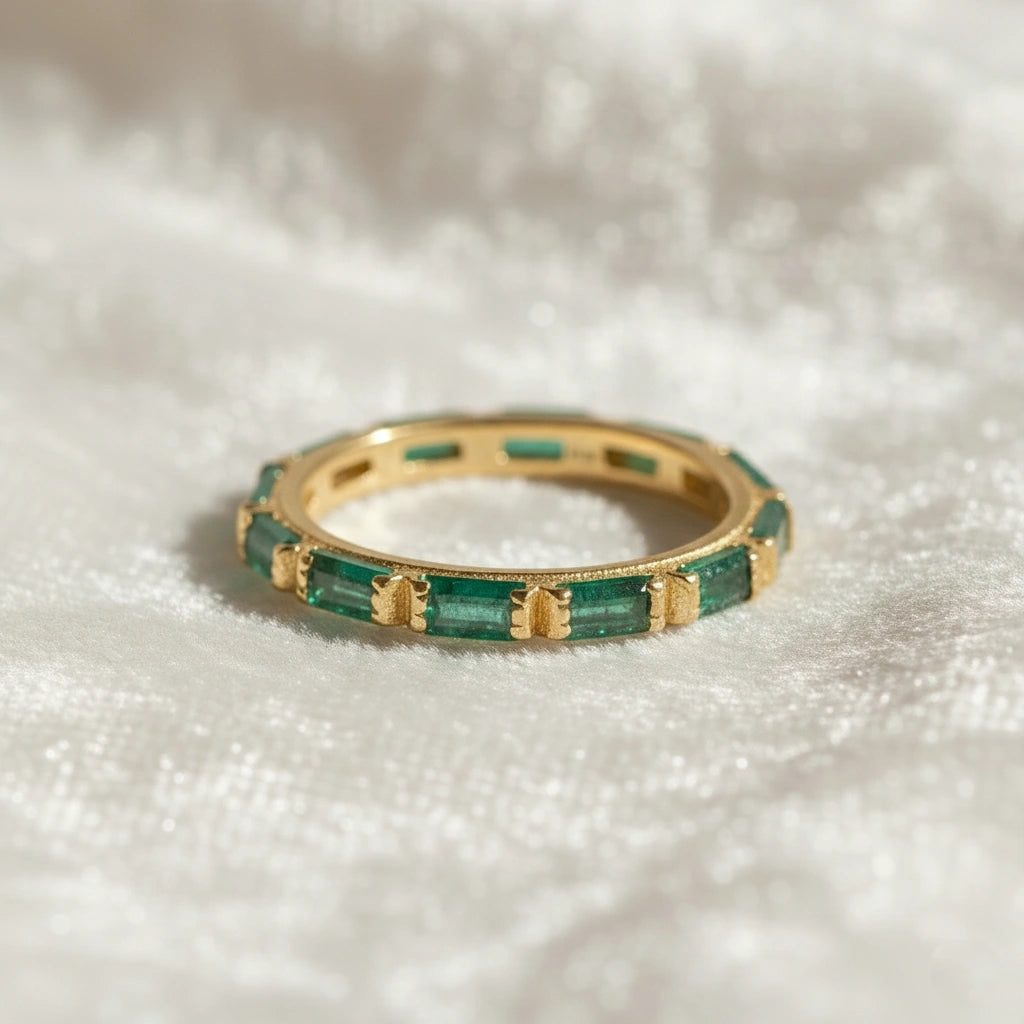 Gold-plated sterling silver green onyx ring with baguette stones bar set low angle view on soft white velvet fabric background