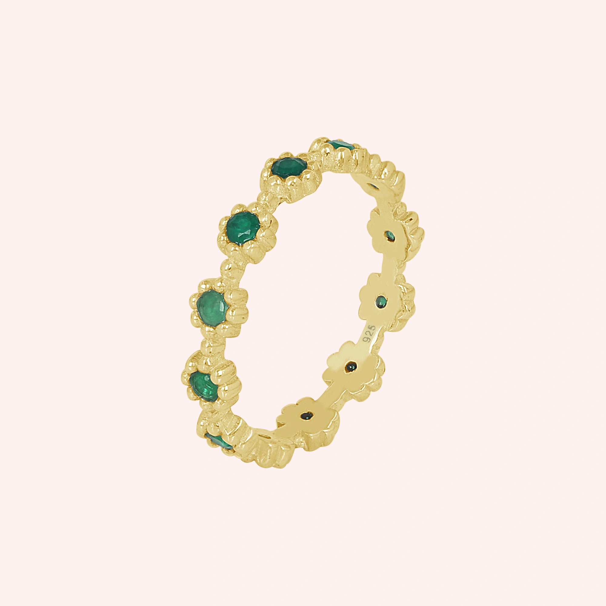 Angled gold vermeil onyx eternity ring on a soft pink background featuring exquisite green onyx gemstones capturing radiant elegance.
