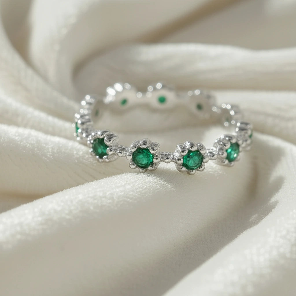 Close up angled sterling silver onyx eternity ring on draped white fabric showcasing vibrant green onyx gemstones beautifully.