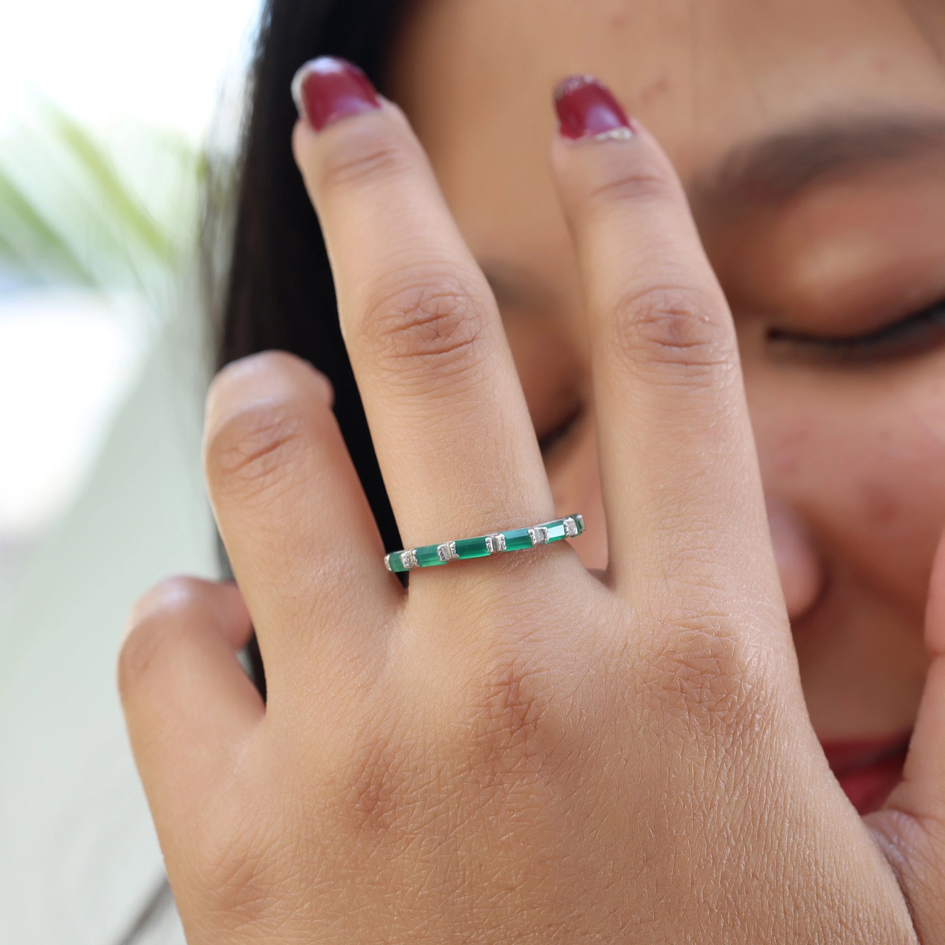 Sterling silver green onyx ring baguette bar set with clear accents on finger close up view model touching face background