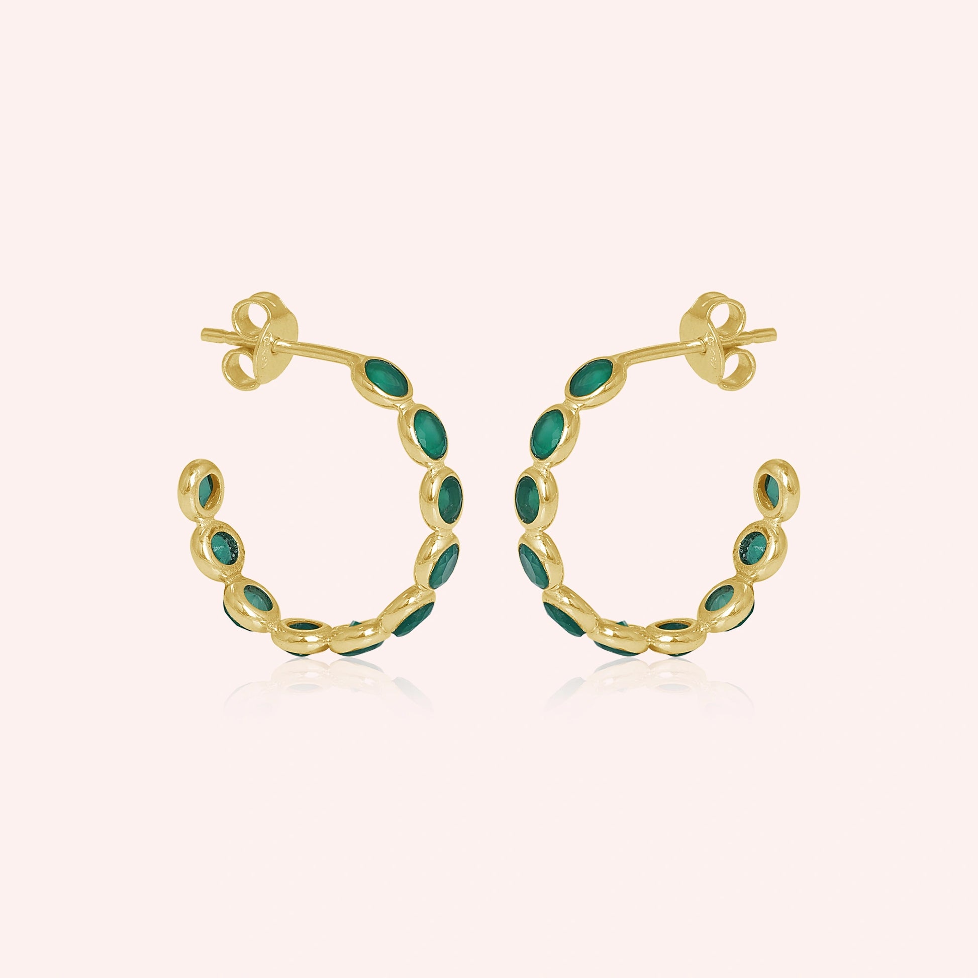 Gold vermeil onyx hoop earrings featuring green stones a beautiful product focus on a light pink background straight on view.