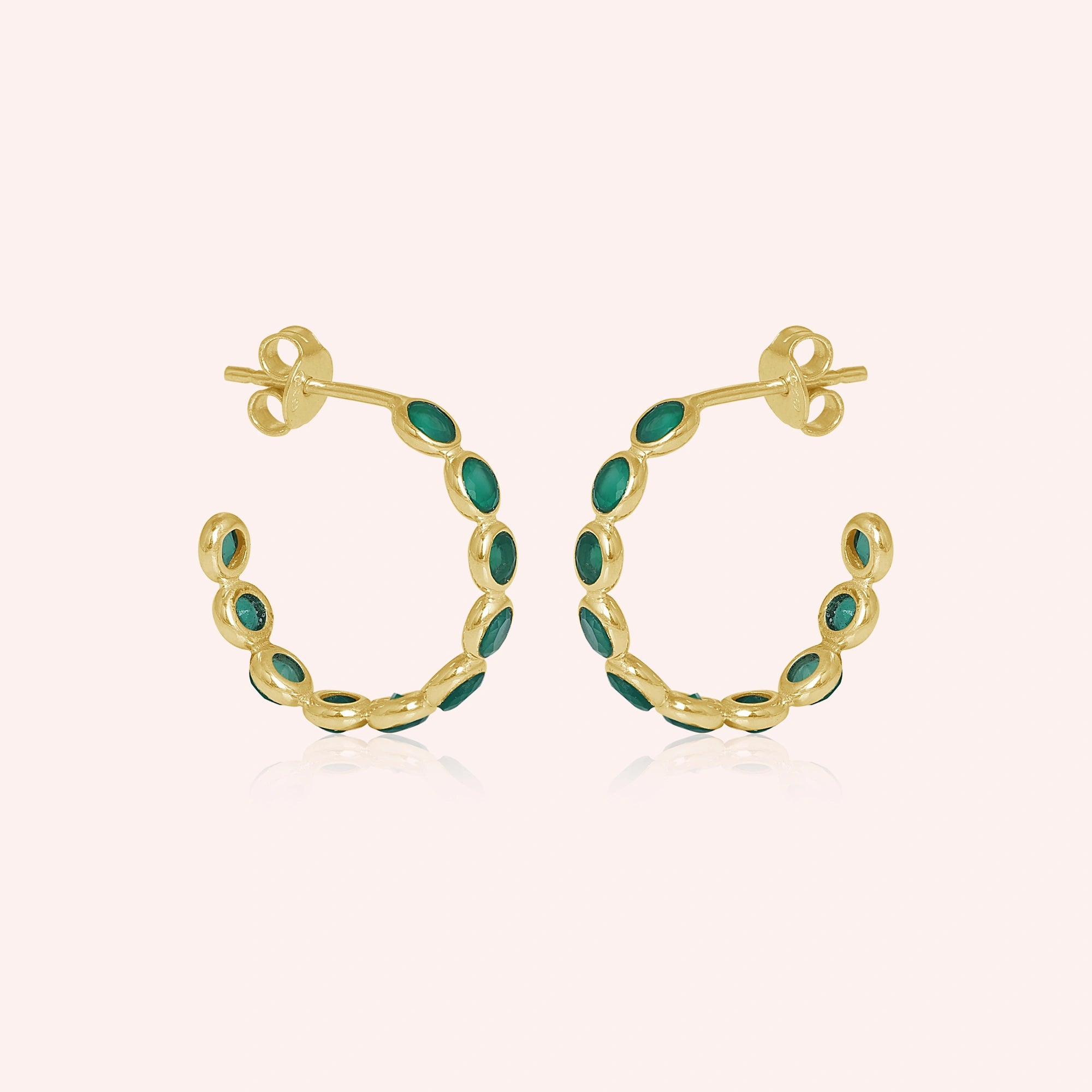 Gold vermeil onyx hoop earrings featuring green stones a beautiful product focus on a light pink background straight on view.