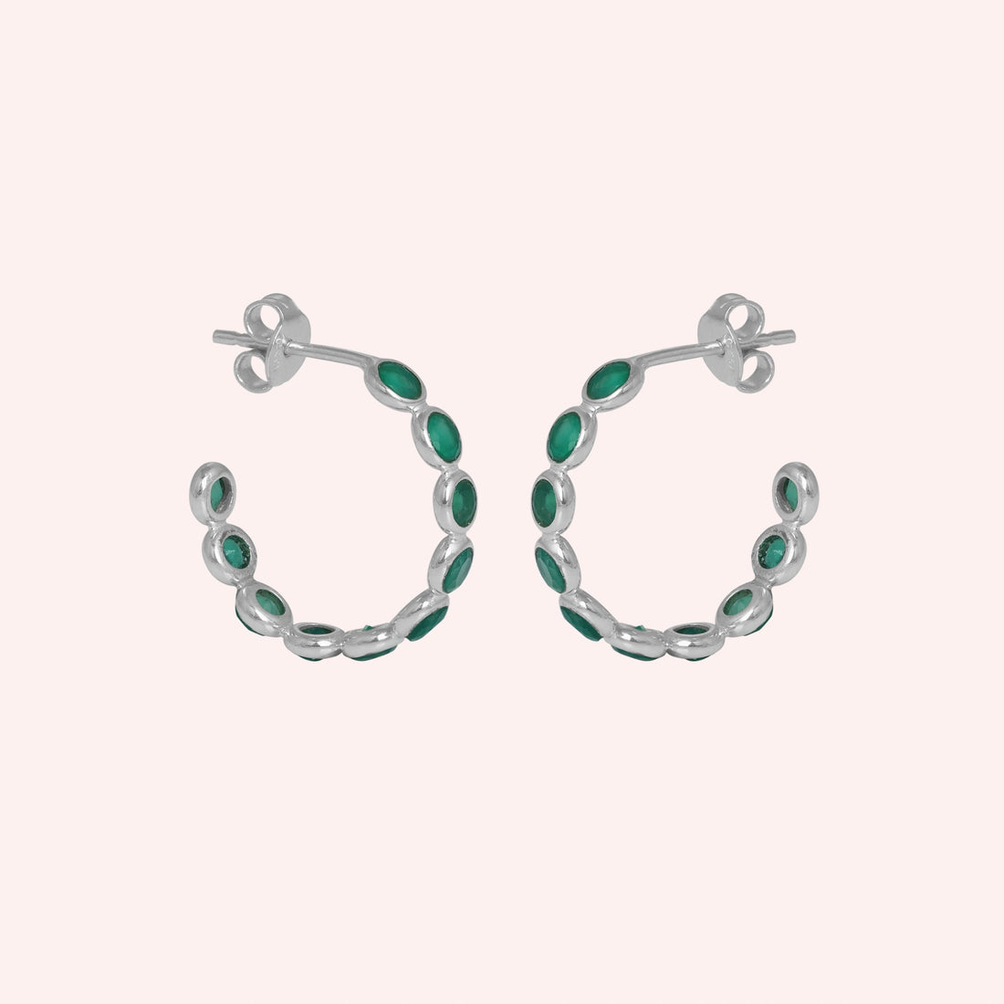 Sterling silver hoop earrings with bright green onyx stones on a wrinkled off white velvet fabric background angled for detail.