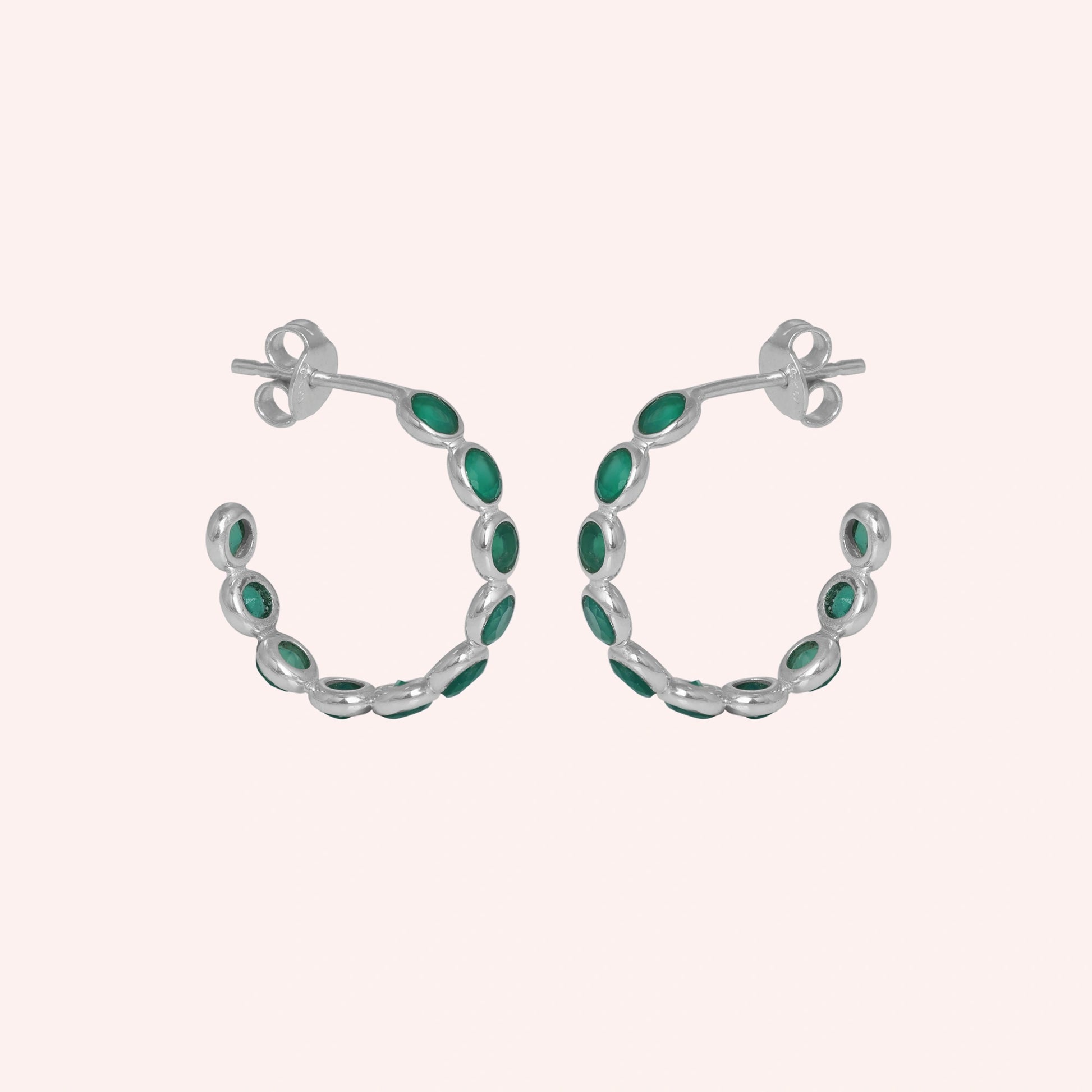 Sterling silver hoop earrings with bright green onyx stones a beautiful product focus on a light pink background straight on view.