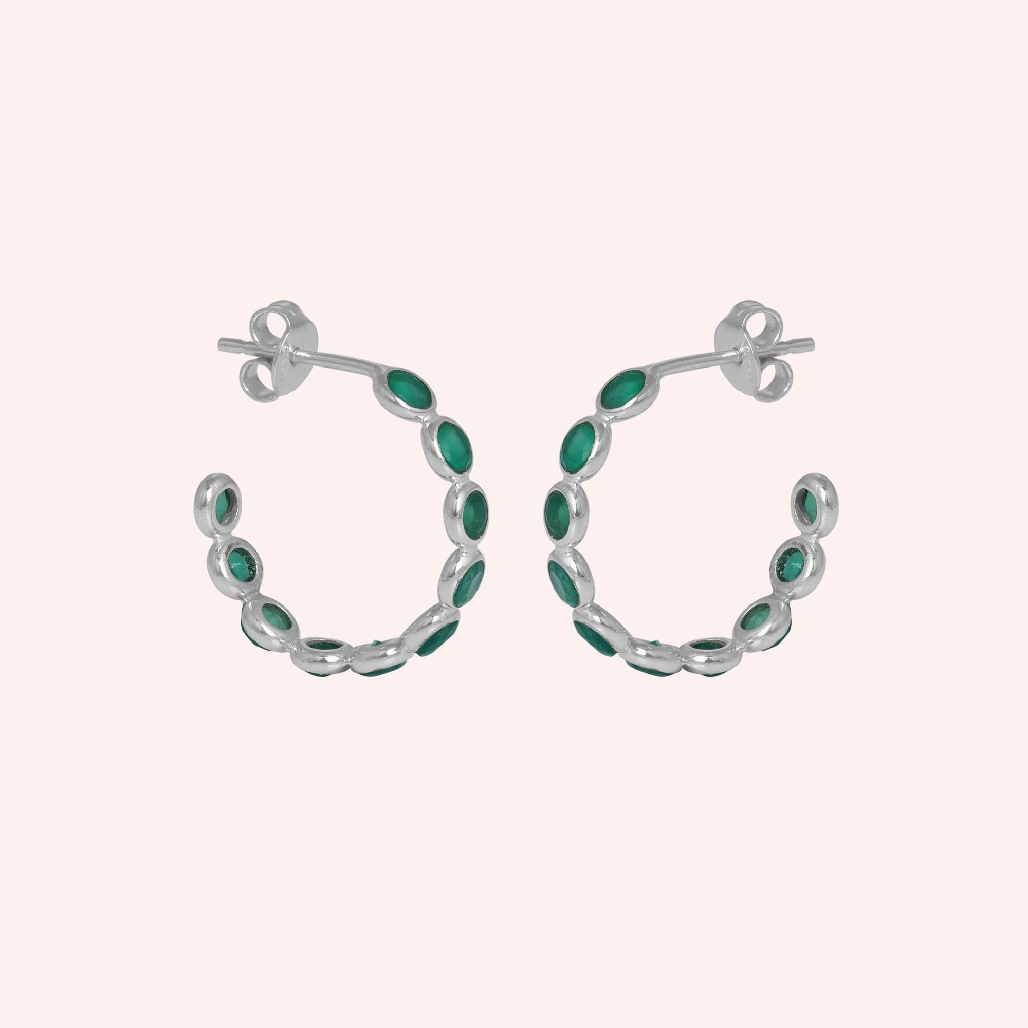 Sterling silver hoop earrings with bright green onyx stones a beautiful product focus on a light pink background straight on view.