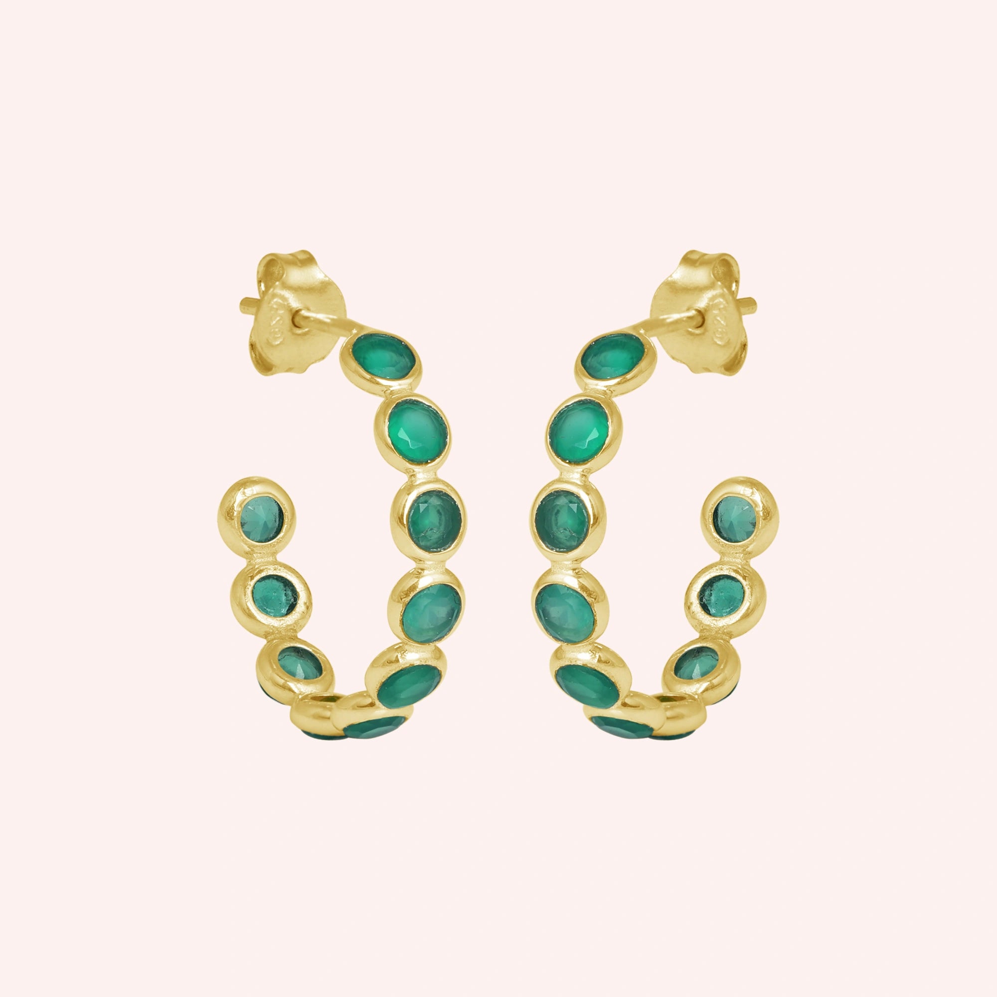 Gold vermeil onyx hoop earrings featuring green stones product focus on a minimal light pink background straight on view.