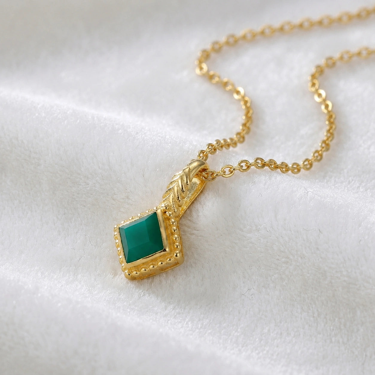 Birthstone_necklace_in_gold_plated_silver_with_square_cut_green_onyx_pendant_in_slighlty_angled_view_on_soft_white_fabric_background