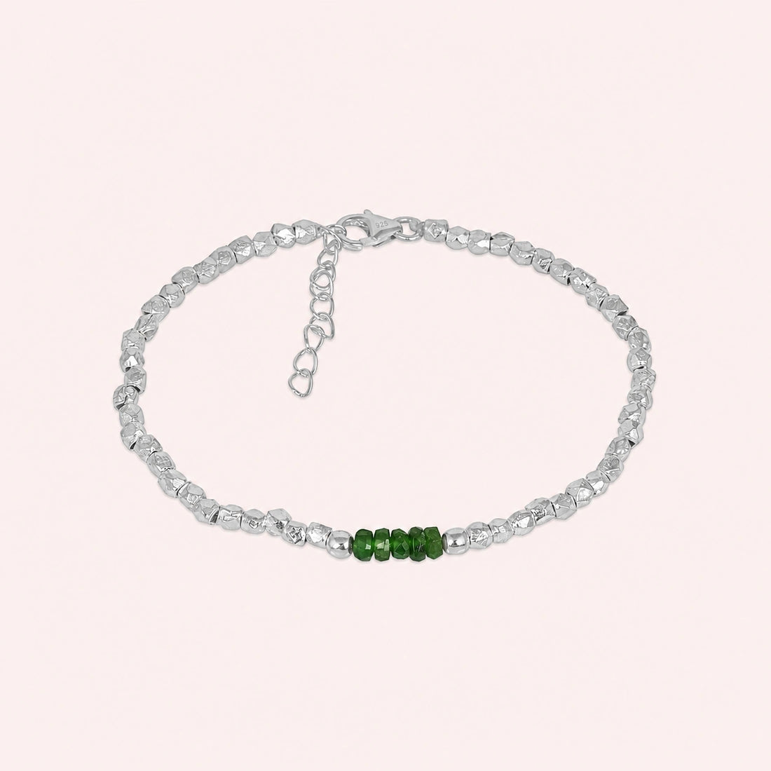Green_stone_bracelet_with_green_onyx_stones_and_gold_plated_silver_beads_at_front_angle_view_on_solid_pink_background
