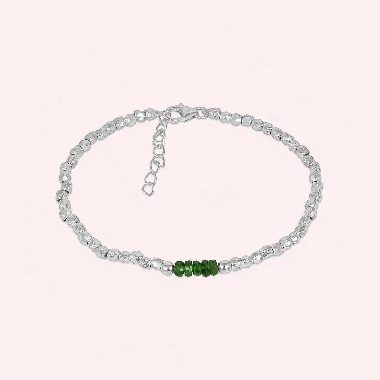 Green_stone_bracelet_with_green_onyx_stones_and_sterling_silver_beads_at_front_angle_view_on_solid_pink_background