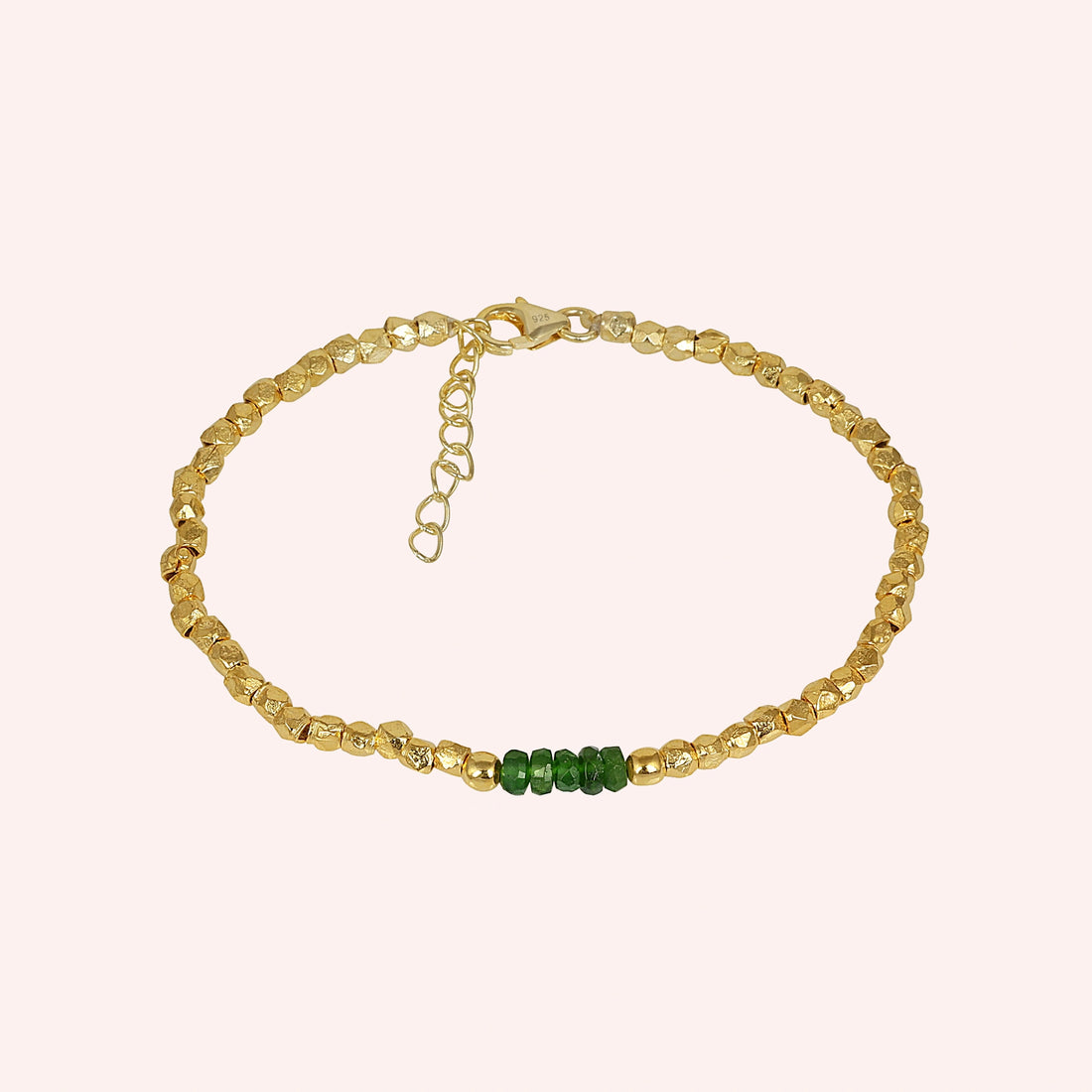 Green_stone_bracelet_with_green_onyx_stones_and_gold_plated_silver_beads_at_front_angle_view_on_solid_pink_background