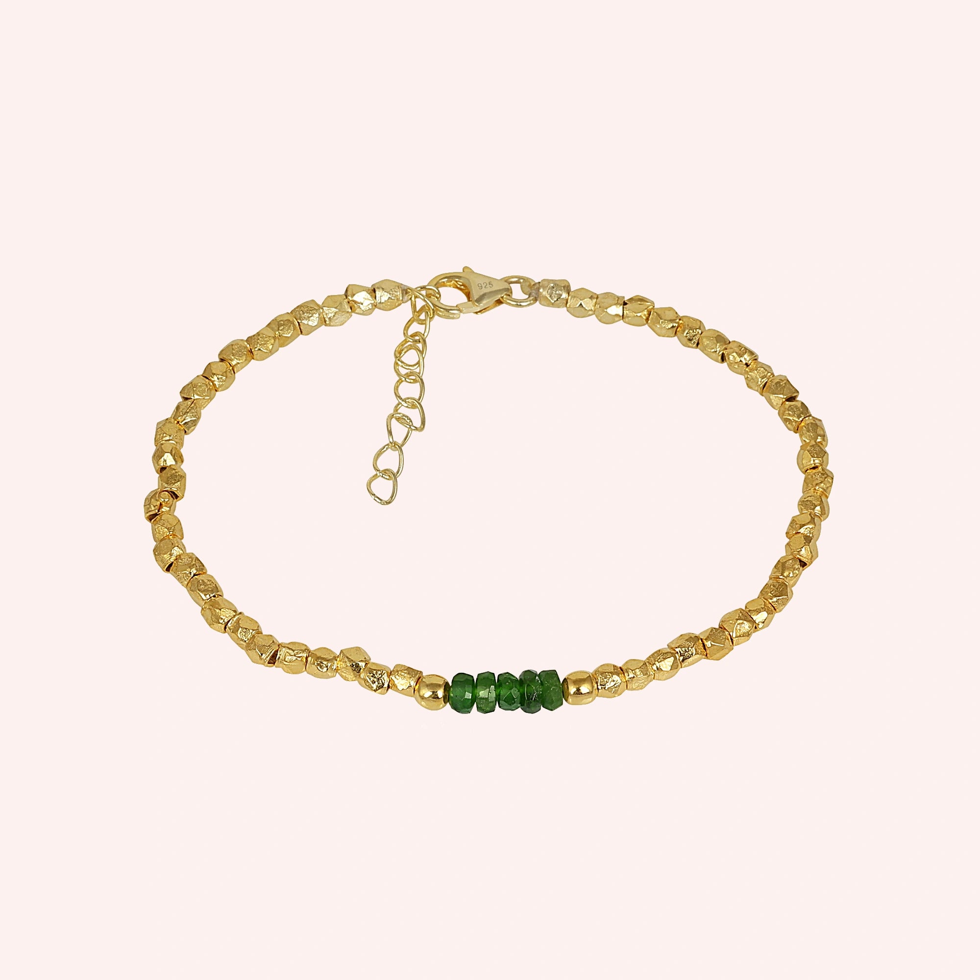 Green_stone_bracelet_with_green_onyx_stones_and_gold_plated_silver_beads_at_front_angle_view_on_solid_pink_background