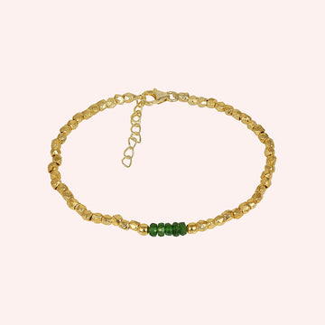 Green_stone_bracelet_with_green_onyx_stones_and_gold_plated_silver_beads_at_front_angle_view_on_solid_pink_background