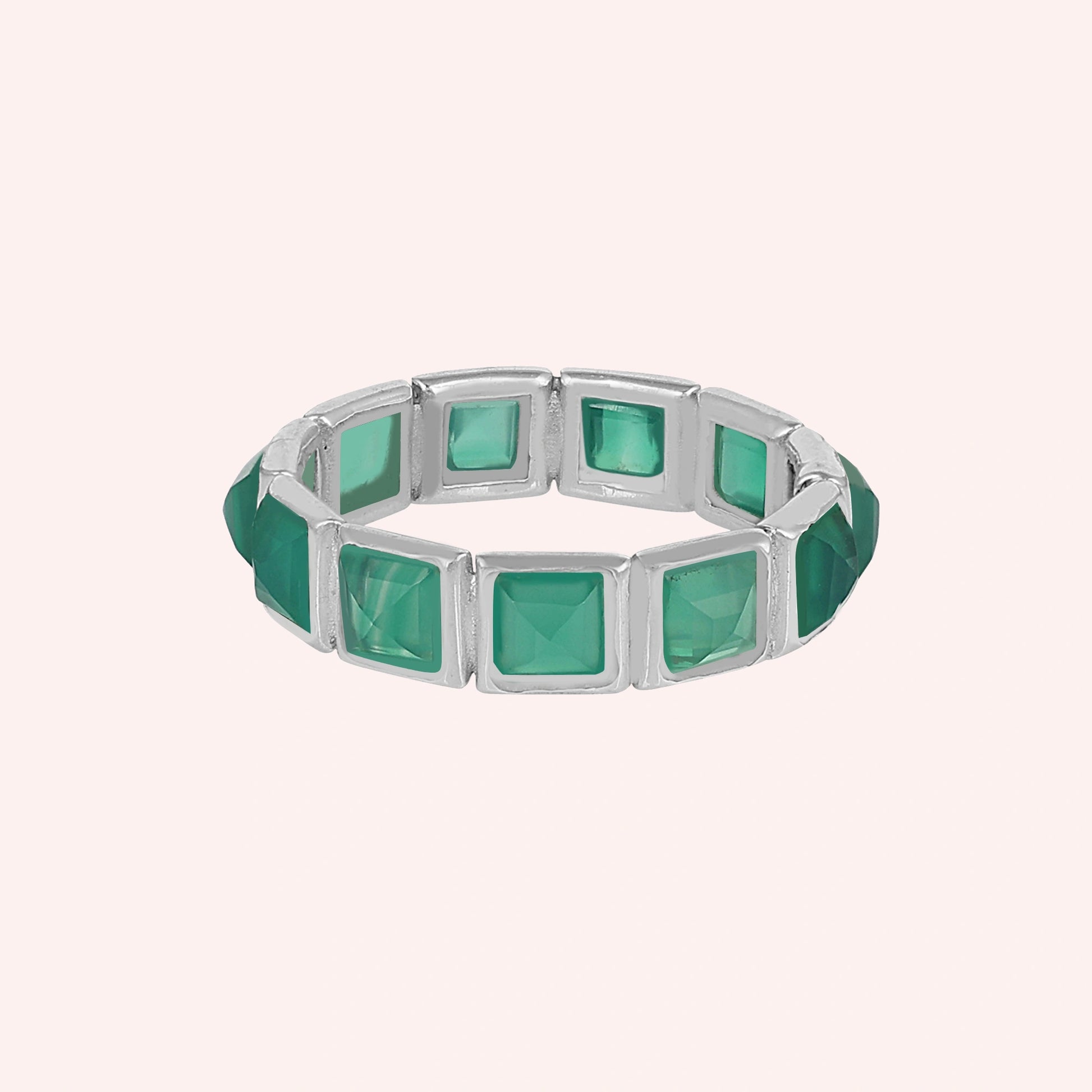 Green onyx ring in a silver eternity band with square stones centered on a plain light pink background.