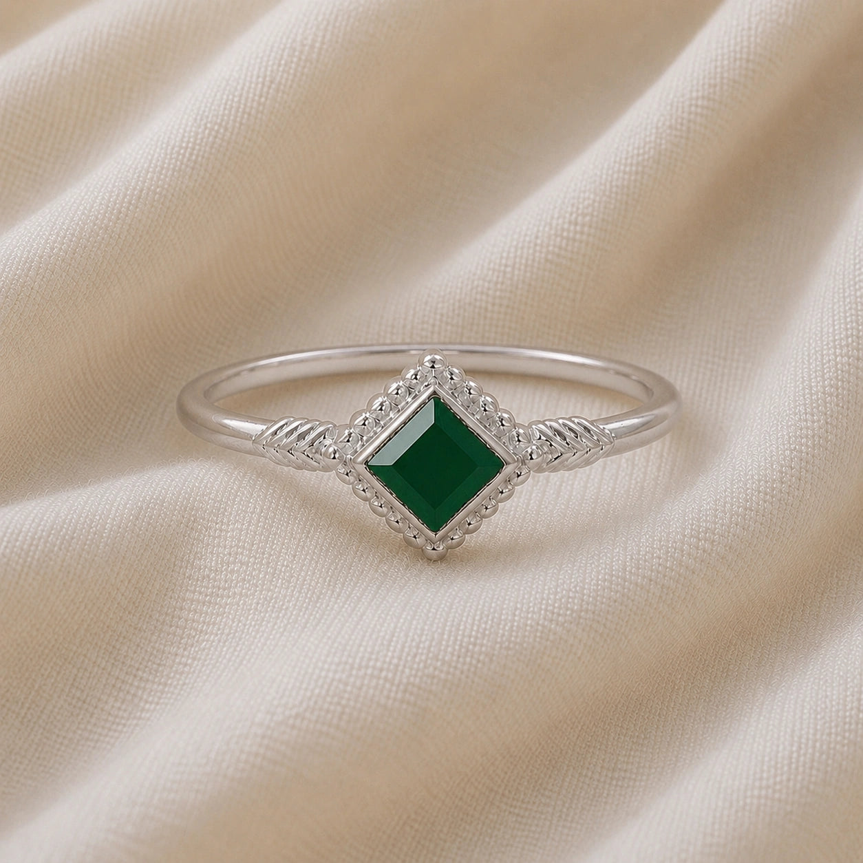 Princess_cut_ring_sterling_silver_with_square_green_onyx_and_detailed_band_front_angle_view_on_soft_fabric_background