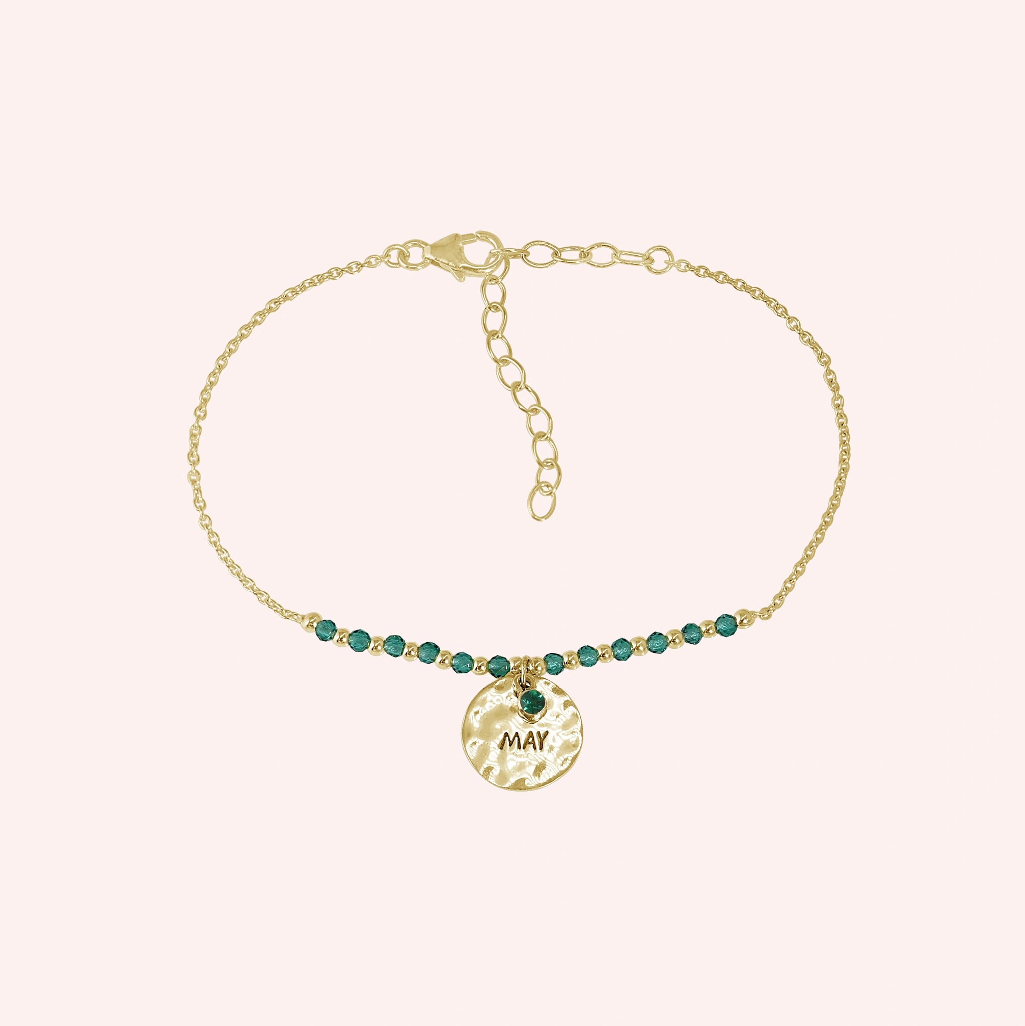 Birthstone_bracelet_in_gold_plated_silver_with_May_charm_and_green_onyx_beads_on_fine_chain_on_solid_pink_background