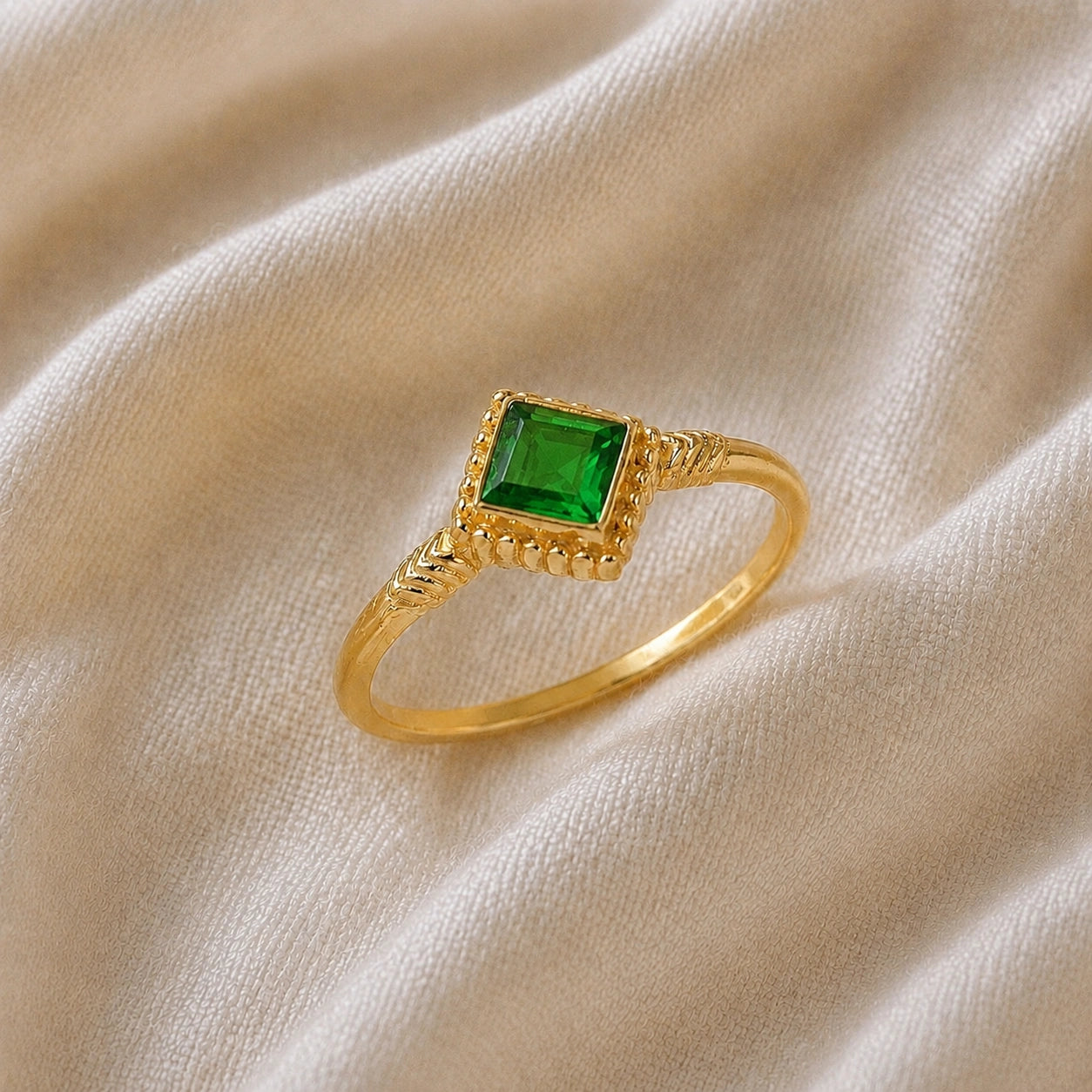 Princess_cut_ring_gold_plated_silver_with_square_green_tourmaline_and_detailed_band_slightly_tilted_view_on_soft_fabric_background