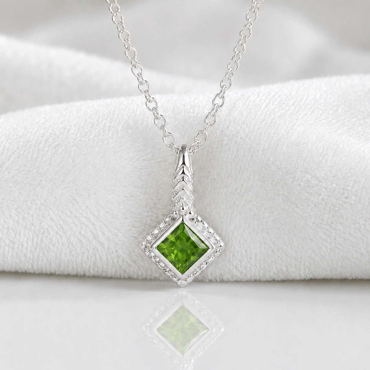 Birthstone_necklace_in_sterling_silver_with_square_cut_green_tourmaline_pendant_in_slighlty_angled_view_on_soft_white_fabric_background