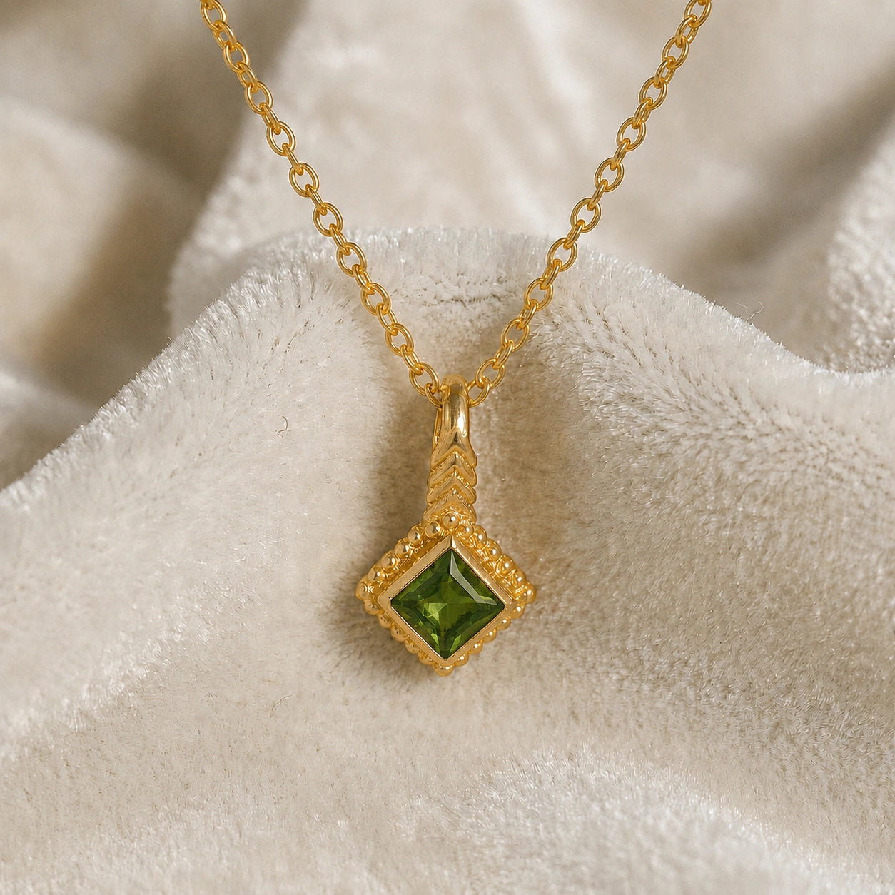 Birthstone_necklace_in_gold_plated_silver_with_square_cut_green_tourmaline_pendant_in_slighlty_angled_view_on_soft_white_fabric_background