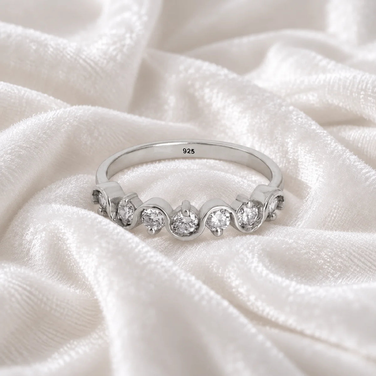 Diamond_ring_in_sterling_silver_with_half_eternity_design_at_front_angle_view_on_soft_fabric_background