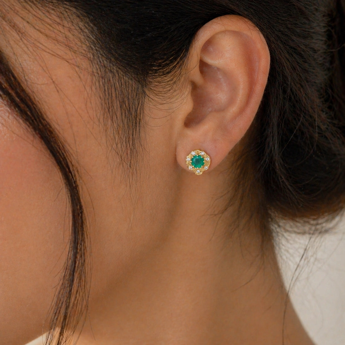 Halo_stud_earrings_in_gold_plated_silver_with_green_onyx_and_white_topaz_stones_at_front_angle_on_soft_fabric_background