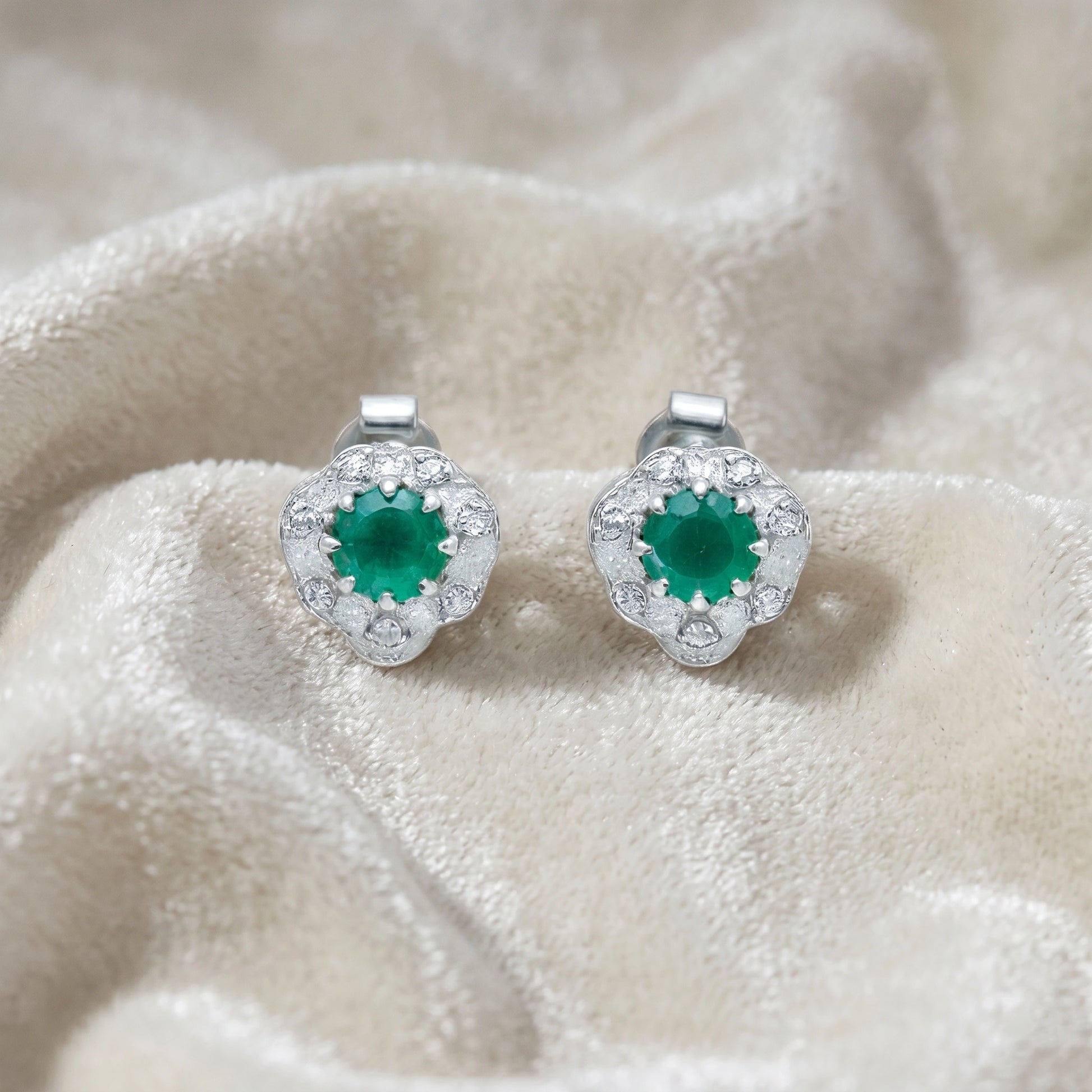 Halo_stud_earrings_in_sterling_silver_with_green_onyx_and_white_topaz_stones_at_front_angle_on_soft_fabric_background