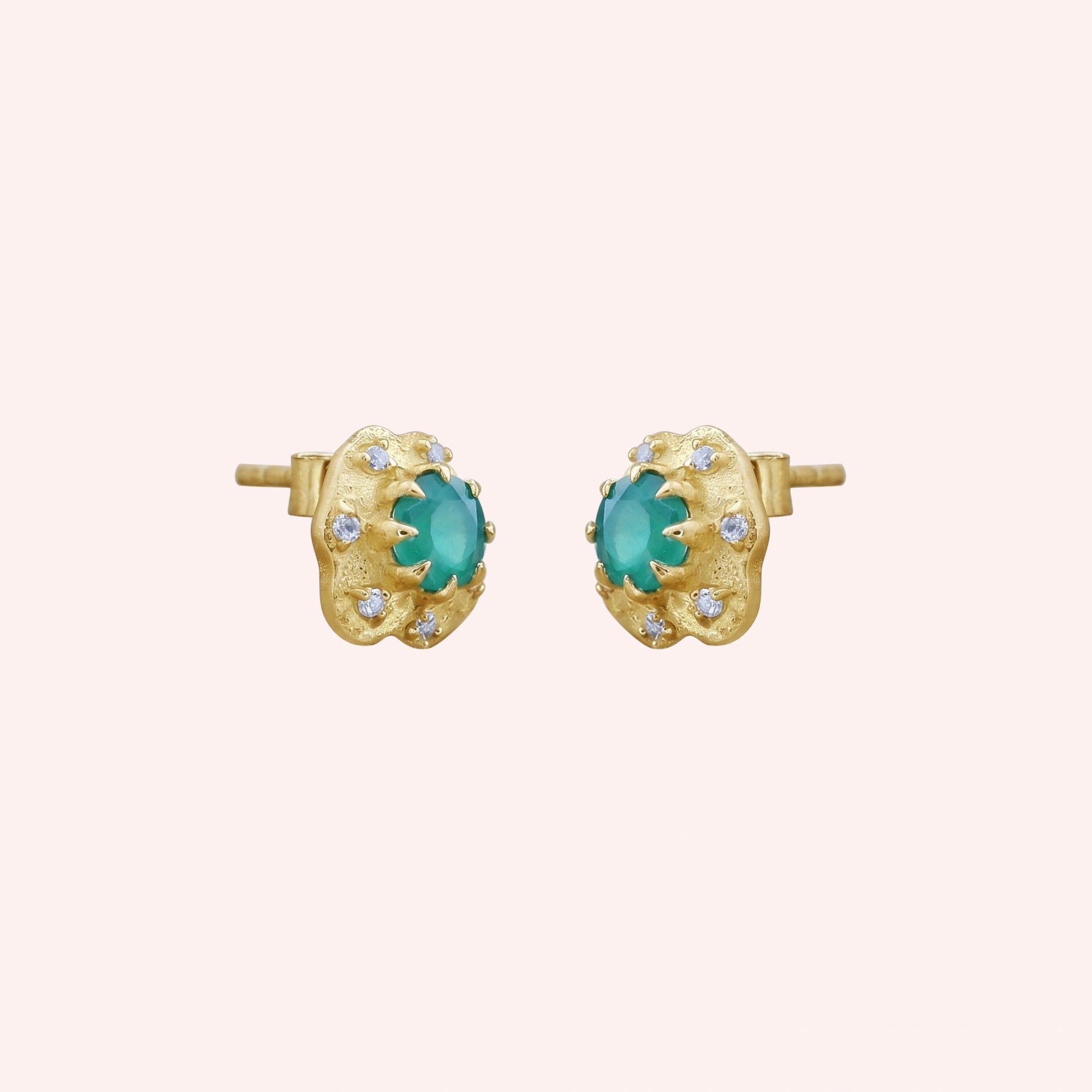 Halo_stud_earrings_in_gold_plated_silver_with_green_onyx_and_white_topaz_stones_at_slightly_angled_view_on_solid-pink_background