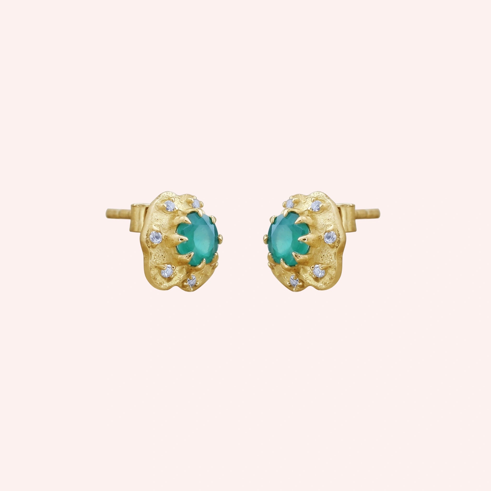 Halo_stud_earrings_in_gold_plated_silver_with_green_onyx_and_white_topaz_stones_at_slightly_angled_view_on_solid-pink_background
