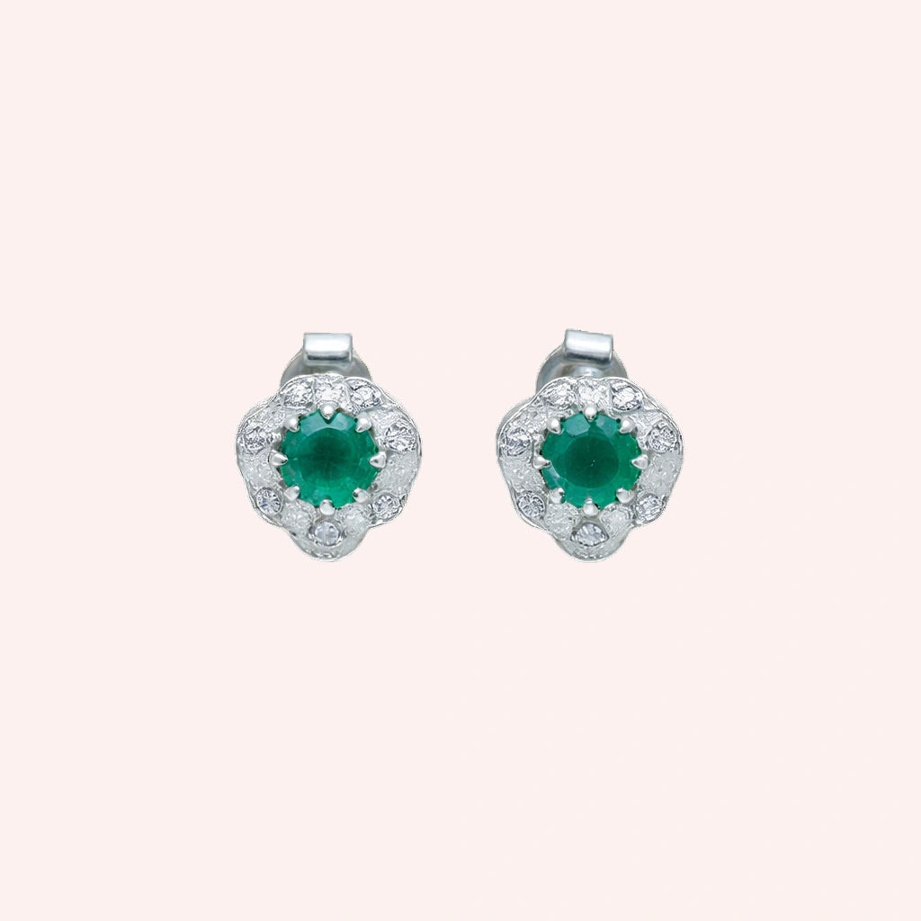 Halo_stud_earrings_in_sterling_silver_with_green_onyx_and_white_topaz_stones_at_front_angle_on_solid_pink_background