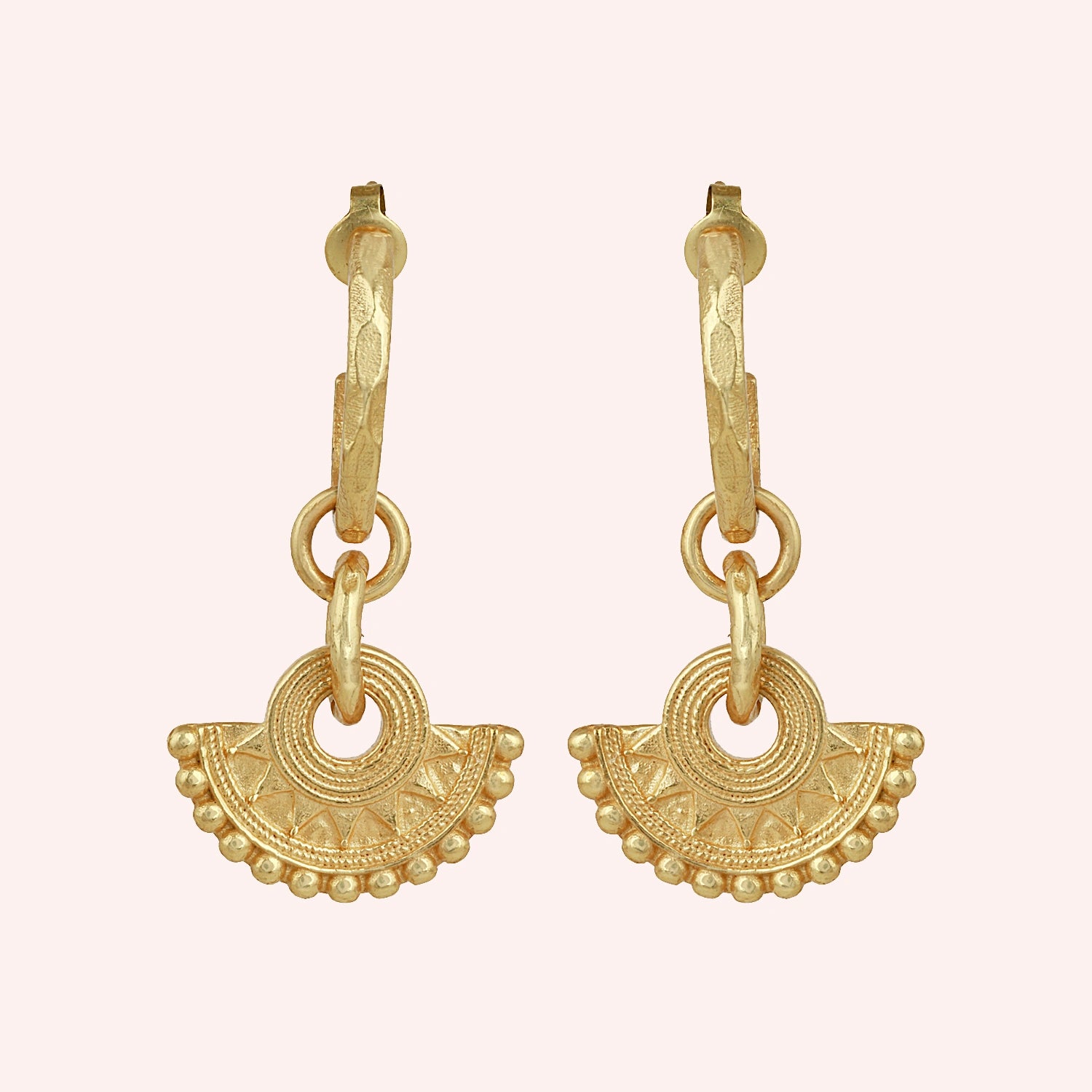 Handmade_earrings_in_gold_plated_silver_with_handcrafted_design_hoops_at_front_angle_on_solid_pink_background